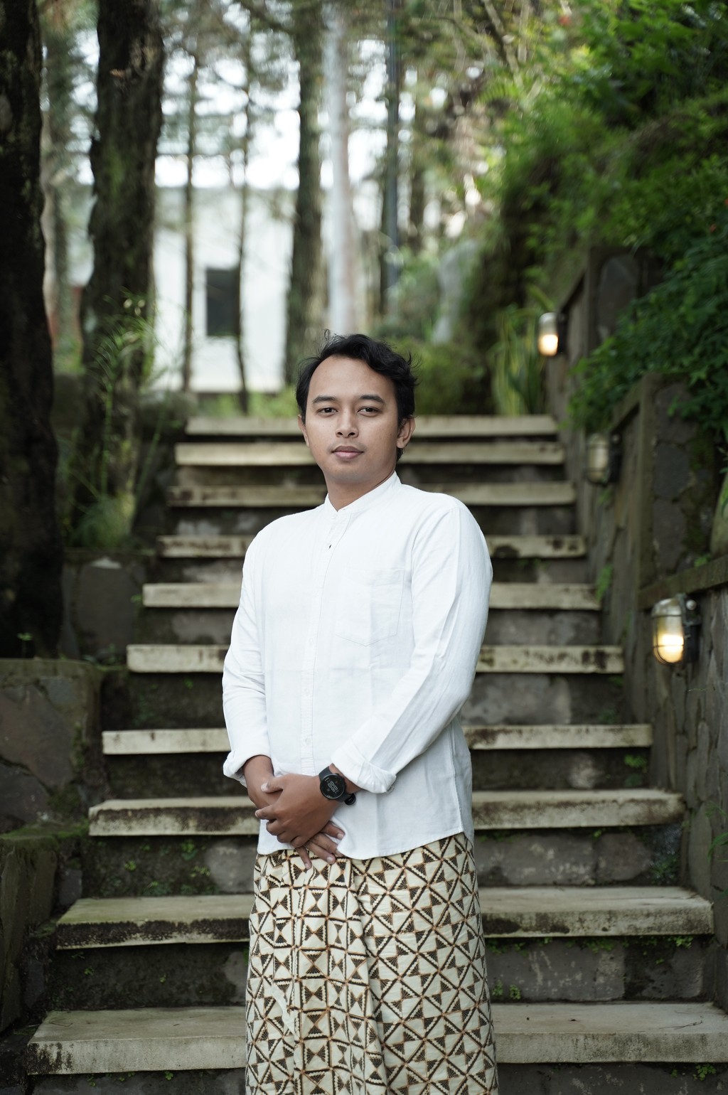 A winding road cuts through rocky terrain, surrounded by patches of green grass and illuminated by sunlight.