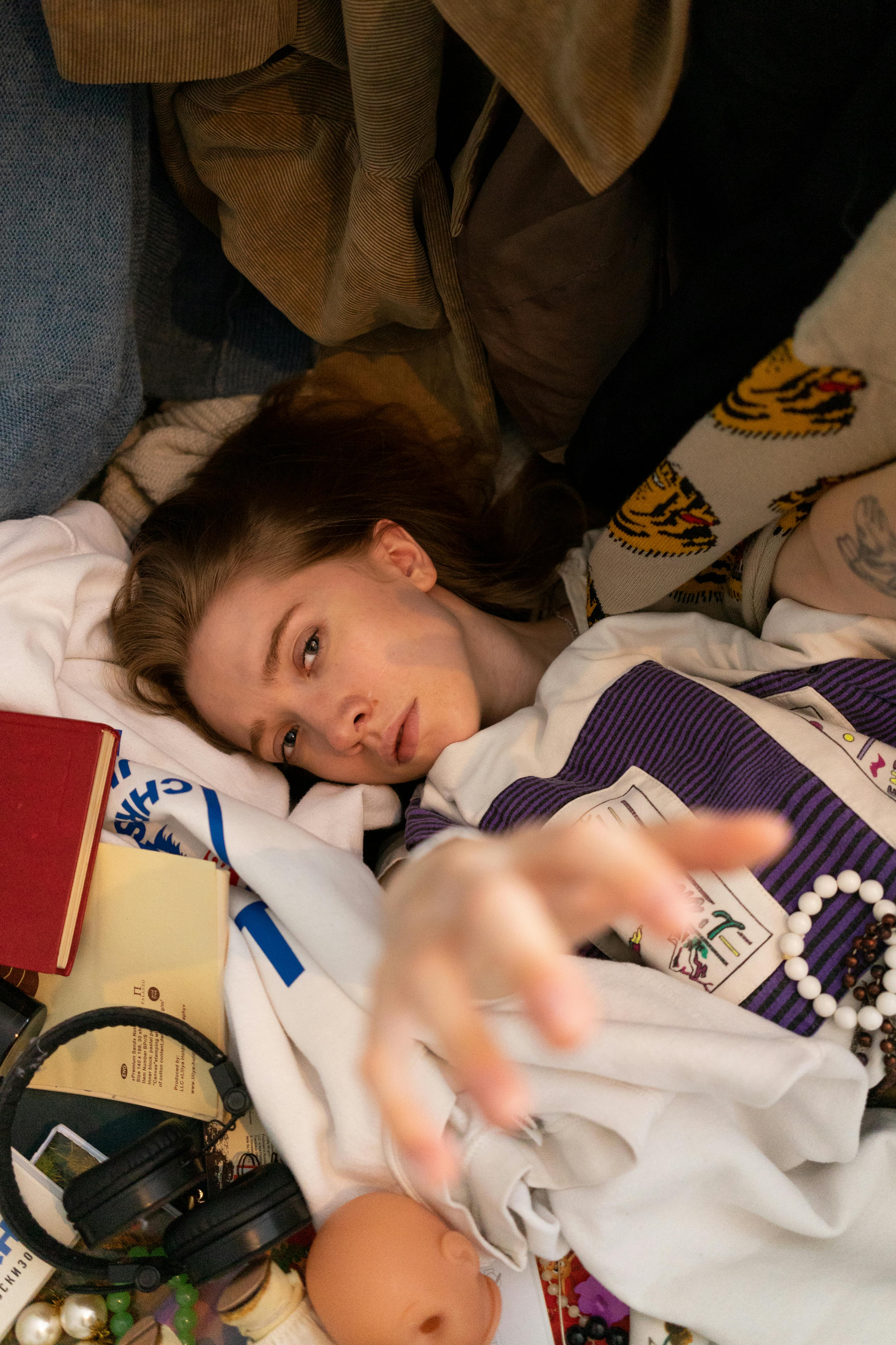 A young woman looks up thoughtfully against dark background.
