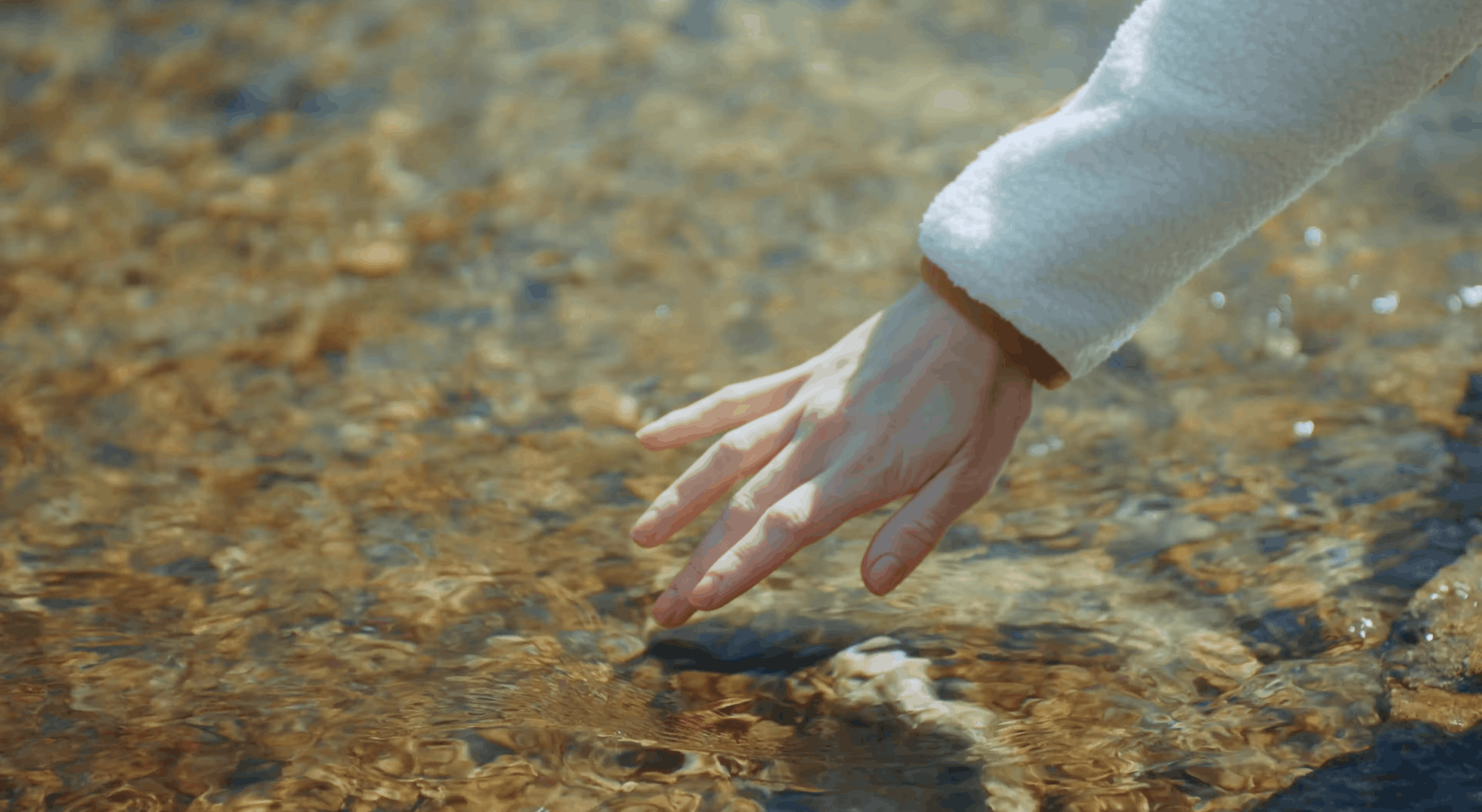 hand touching cold mountain stream in halfdays winter brand film