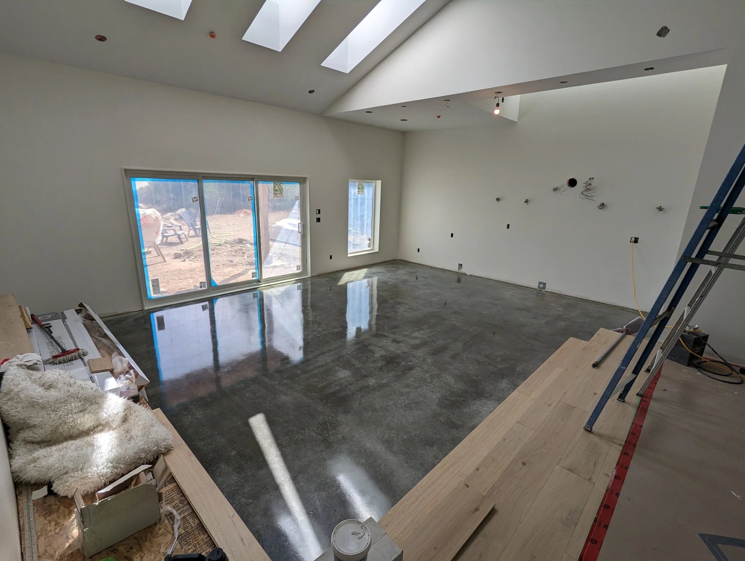 Modern two-story home with large glass windows, warmly lit interiors, and a balcony. Surrounded by trees and a manicured lawn at dusk. Cozy ambiance.