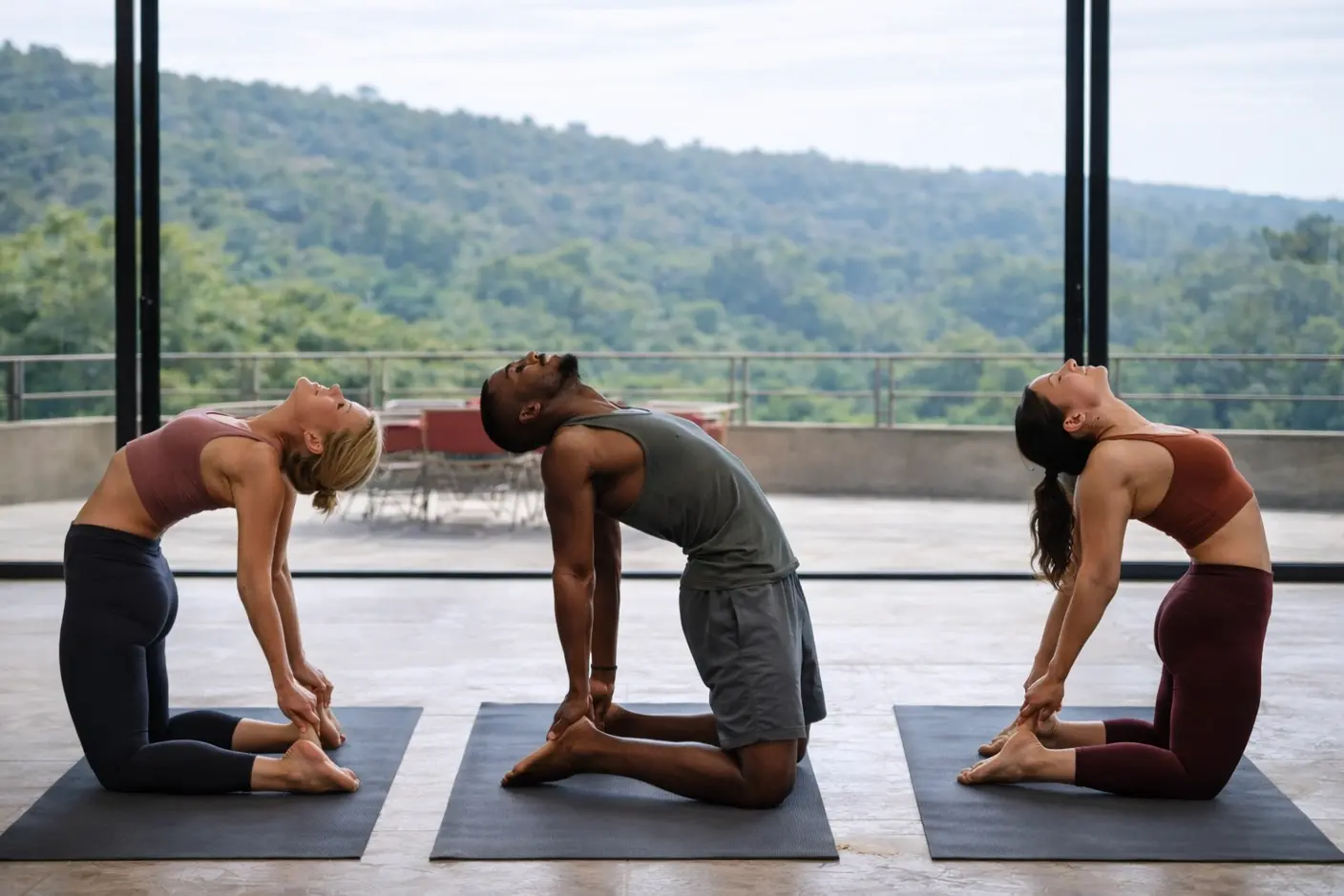 Group practicing Camel Pose (Ustrasana) heart-opening backbend inside the spacious stone villa yoga studio.