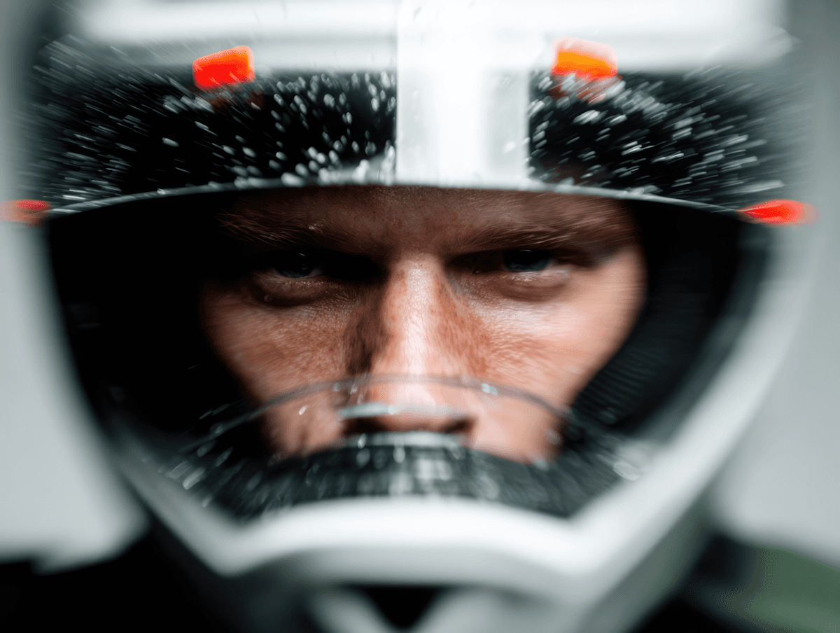 Close-up of a person in a helmet with water droplets on the visor, showcasing their intense gaze and the helmet's detailed design.