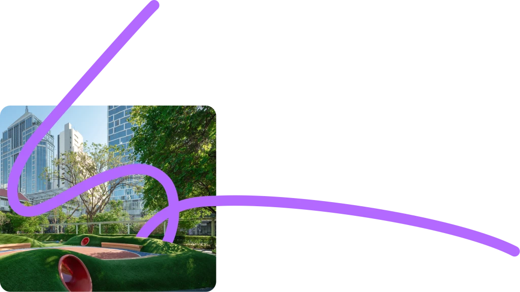 Colorful playground with green structures, a large clock, flowers, and city skyline in the background.