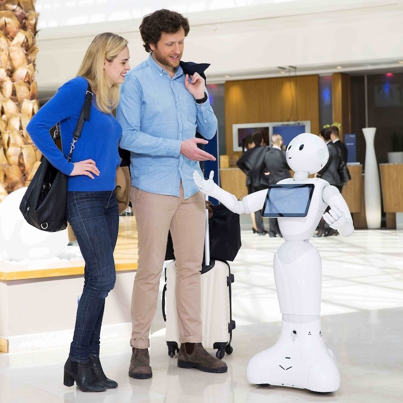 Roboter Pepper begrüßt zwei Gäste in einer Veranstaltungslocation
