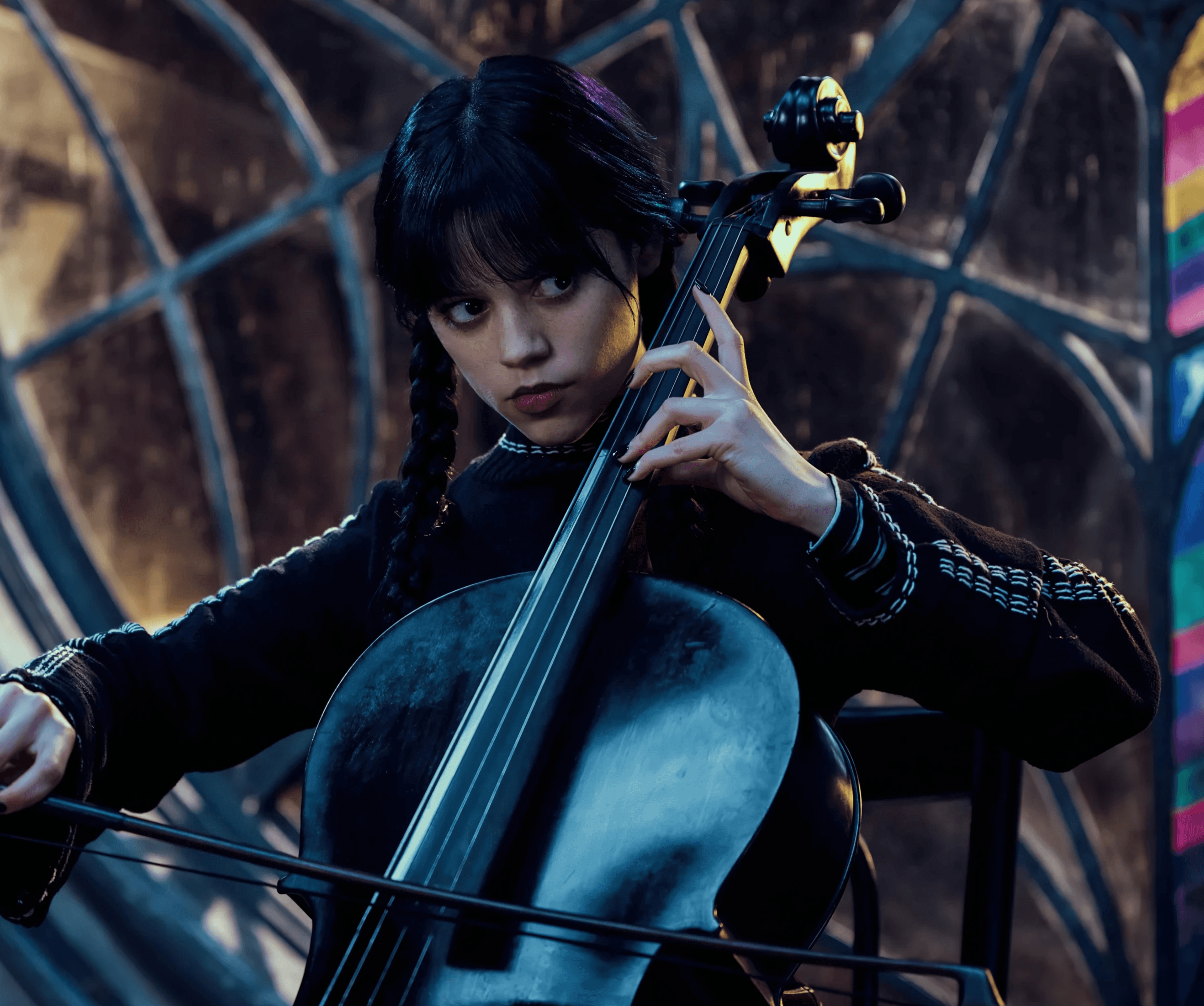 Jenna Ortega as Wednesday Addams in 'Wednesday', playing the cello with a focused expression.