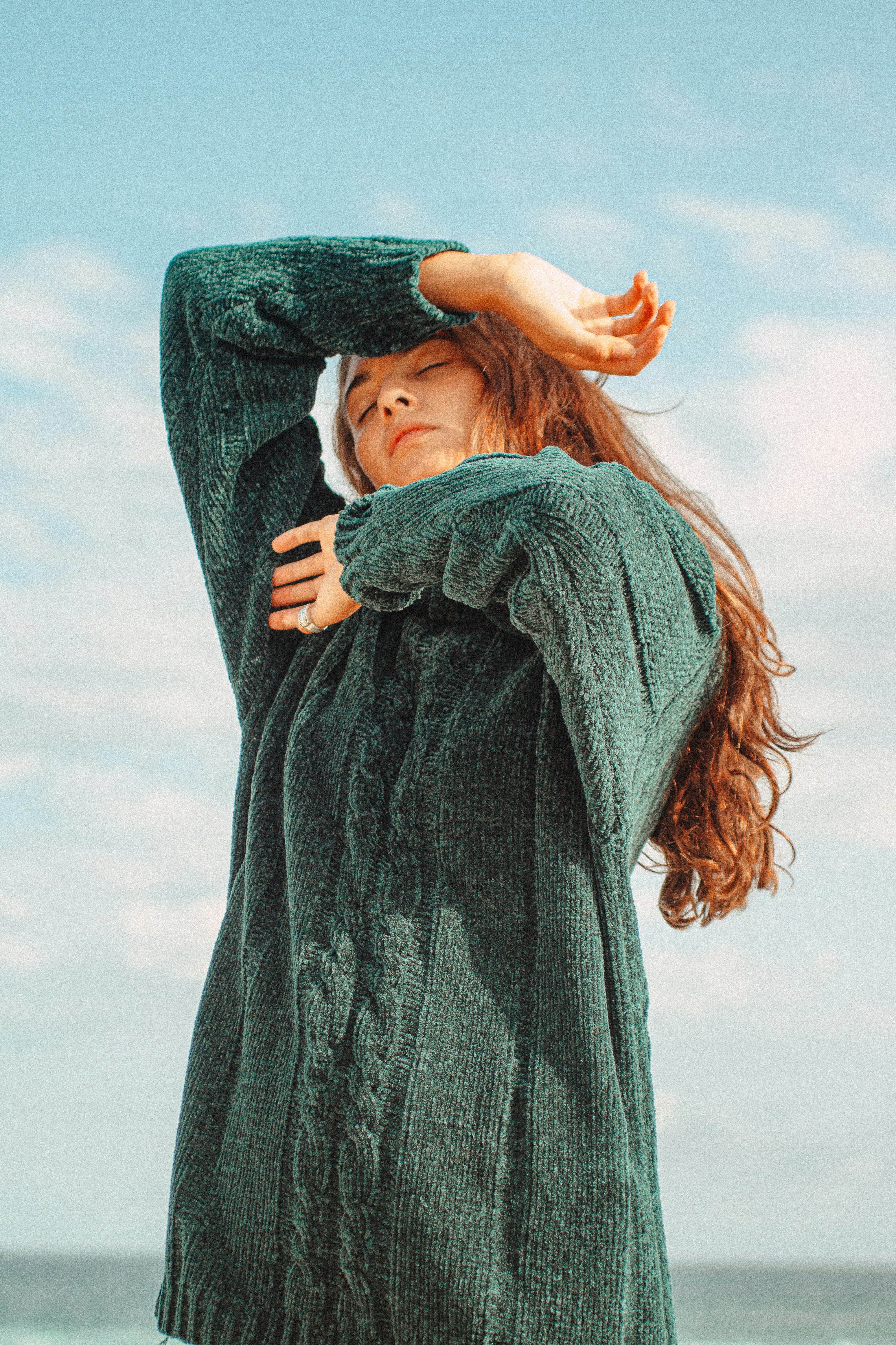 Woman wearing a green sweater in front of blue sky