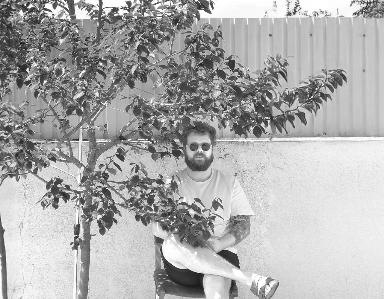 A thoughtful young person with dark hair gazes to the side, captured in soft black and white lighting.