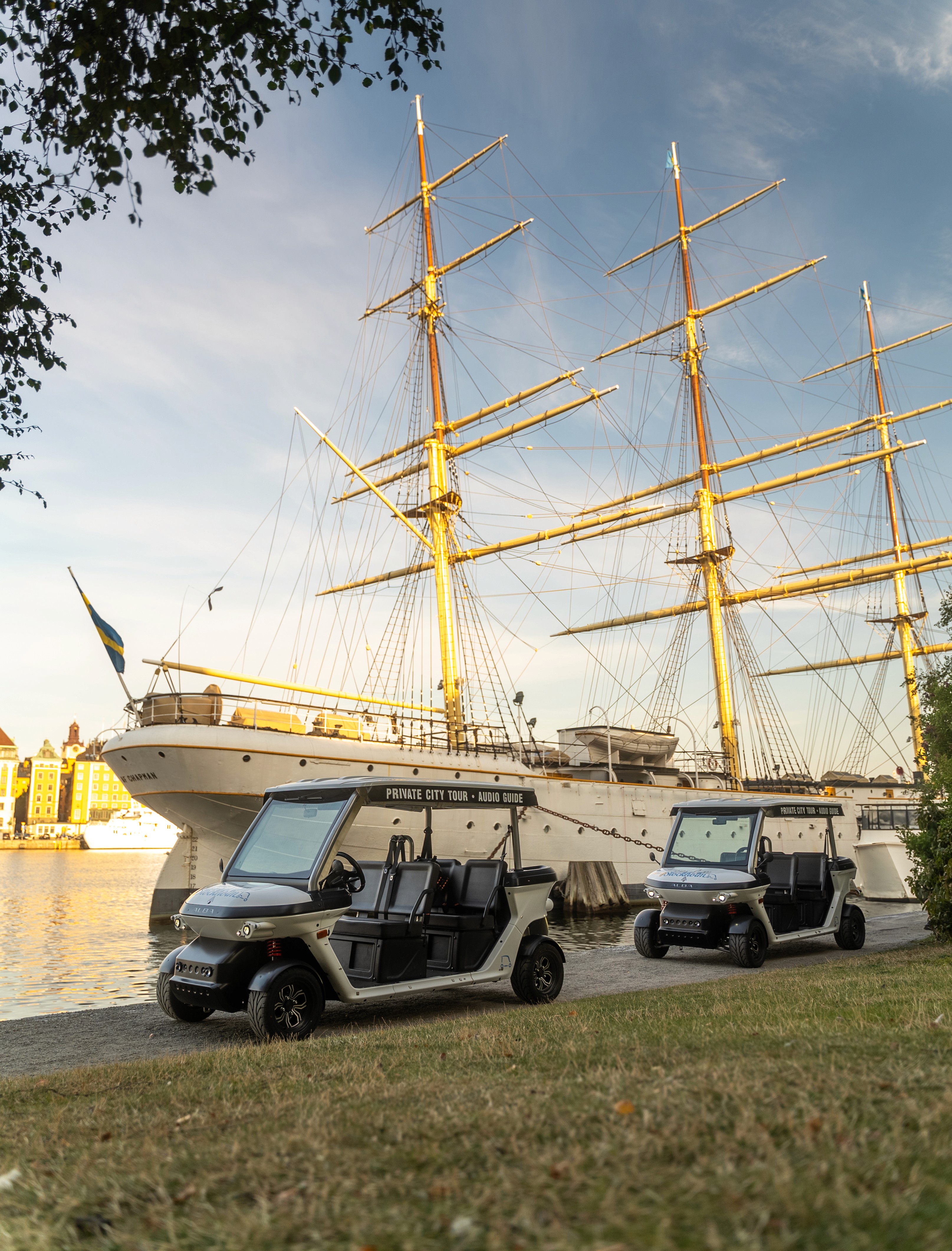 Electric sightseeing carts parked near historic ship in Stockholm harbor