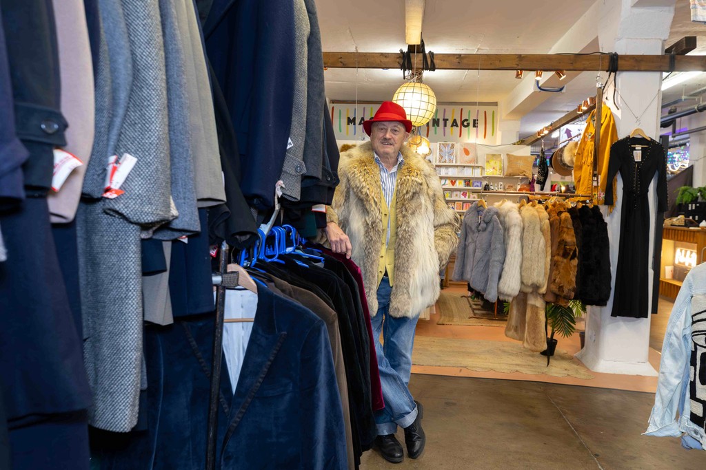 a clothing business owner stands smiling in the middle of the shop