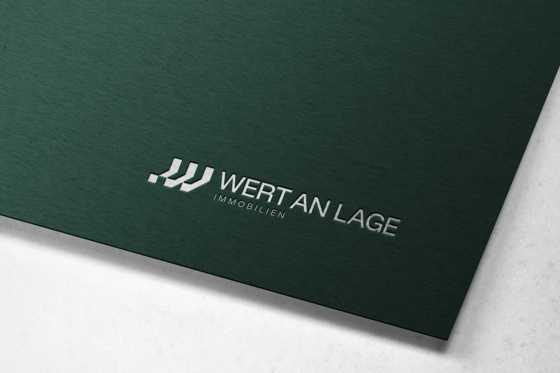Ein Bild vom Logo von Wert an Lage welches auf einem dicken, dunkelgrünen Stück Papier gedruckt ist.