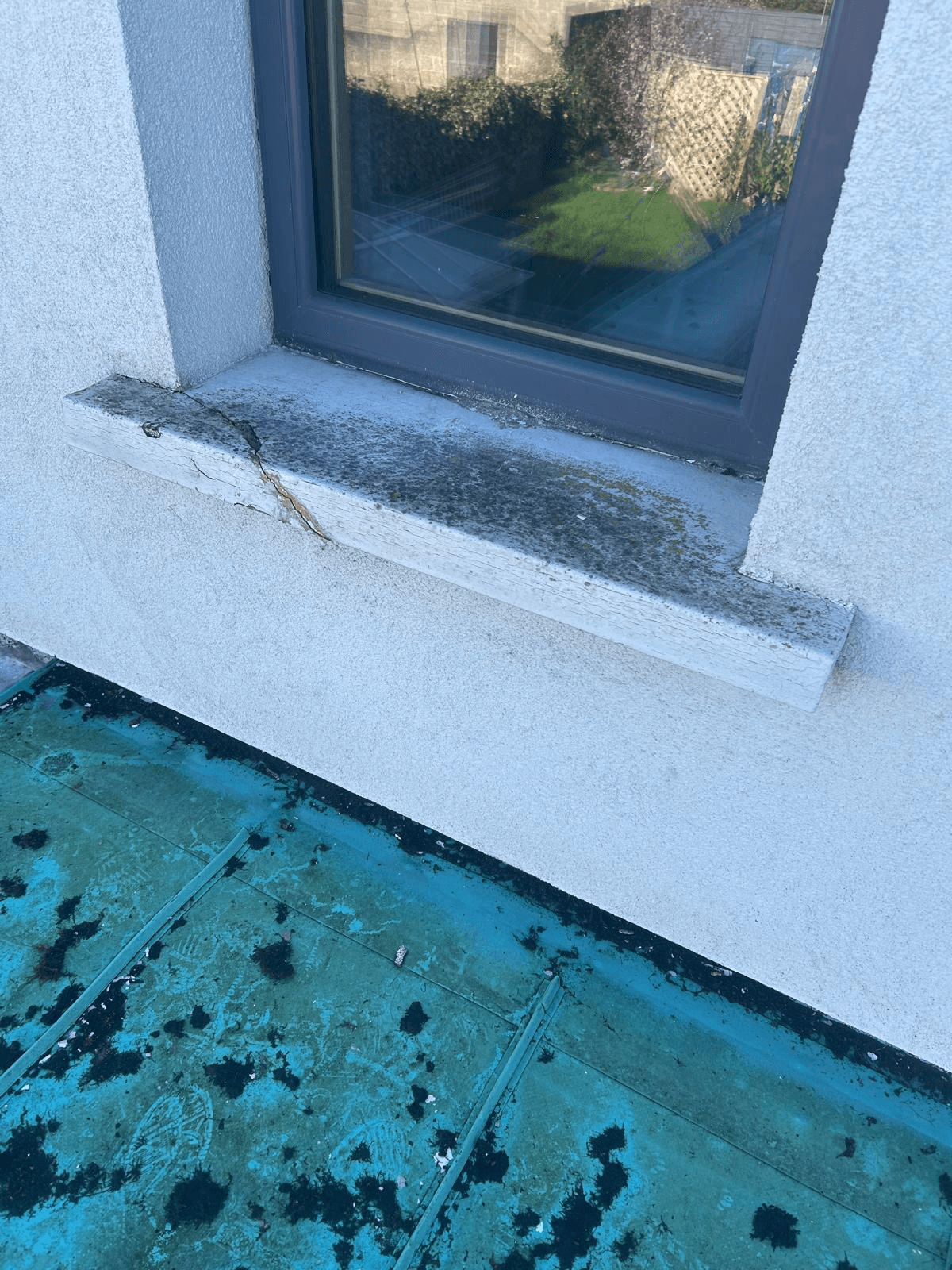 A passive cill that has completely crumbled and fallen off the wall. The concrete coating has disintegrated, leaving the window opening exposed to rain and wind.