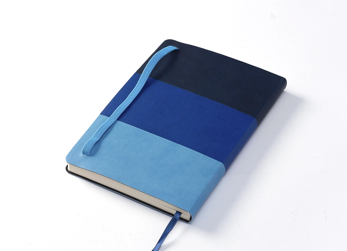 Angled back view of blue color-block notebook with strap.