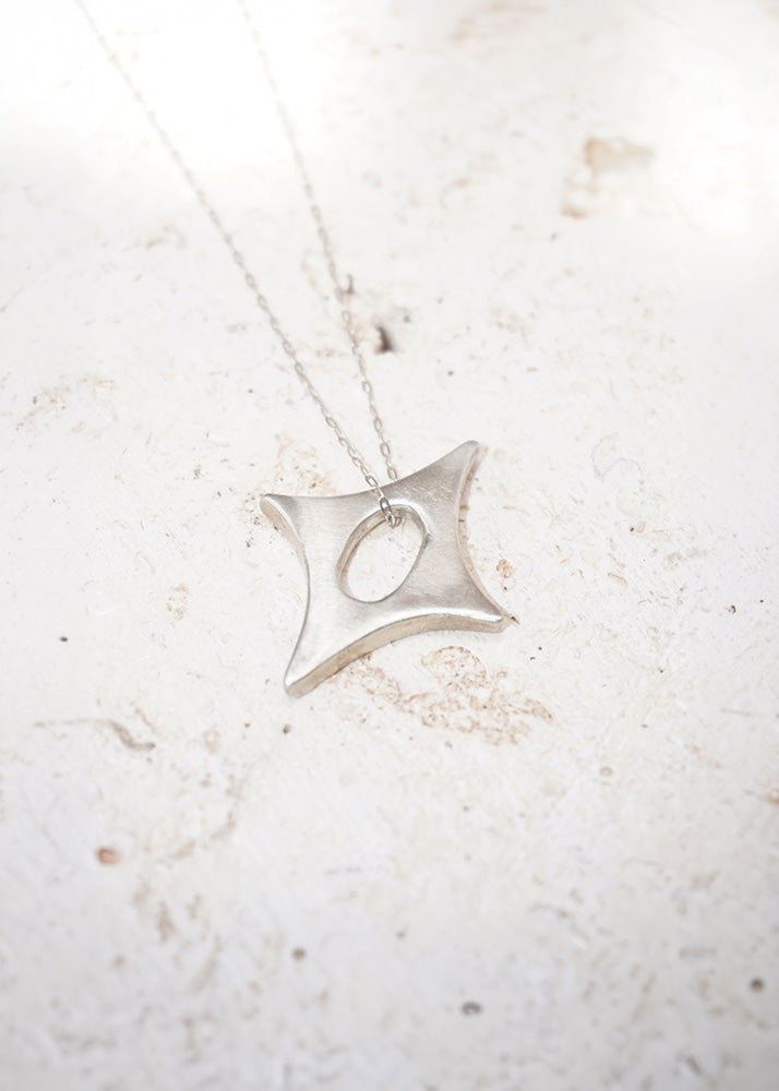 Silver necklace with a star-shaped pendant on a light marble background