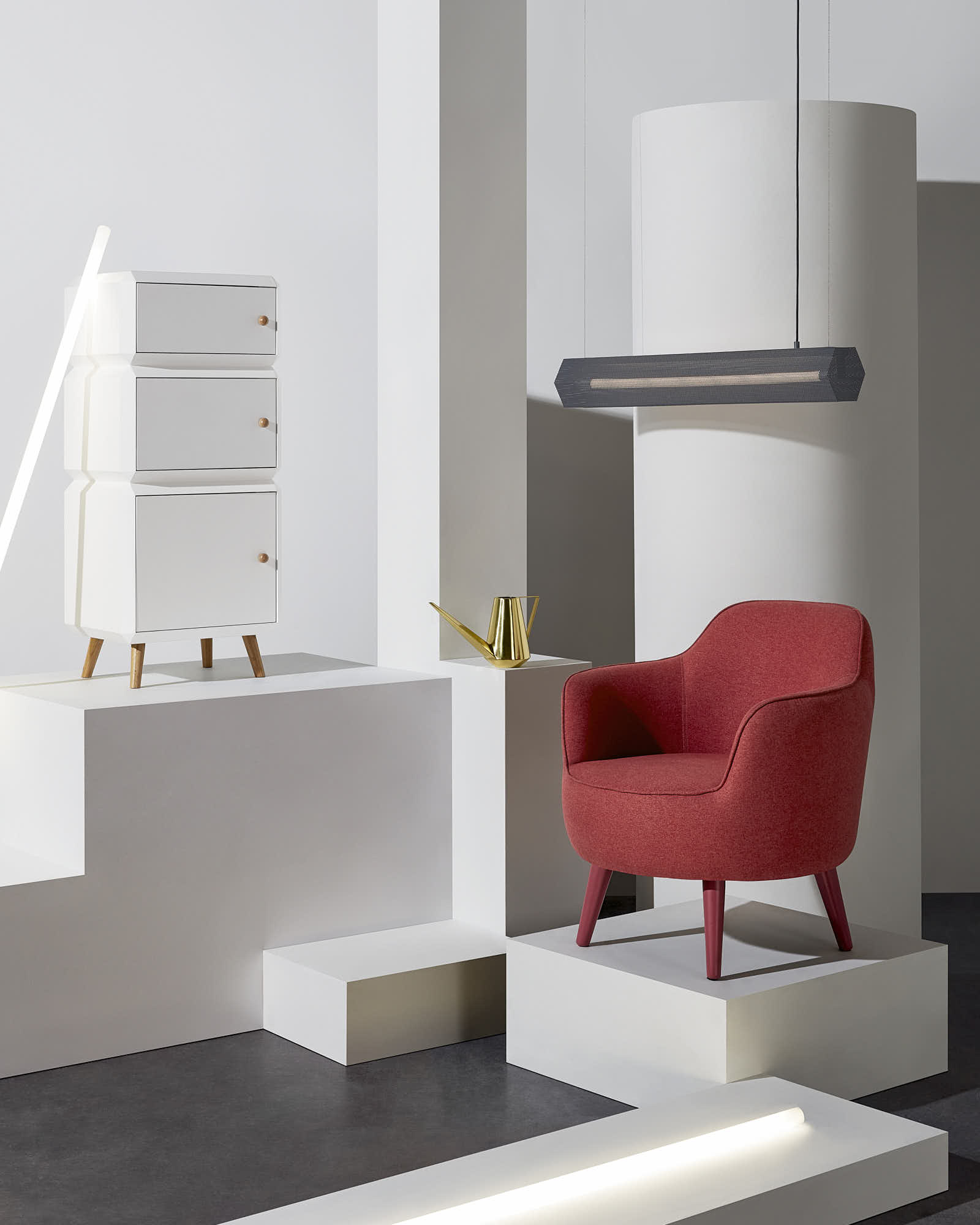 Modern interior design with red armchair, white cabinet, and geometric lighting.