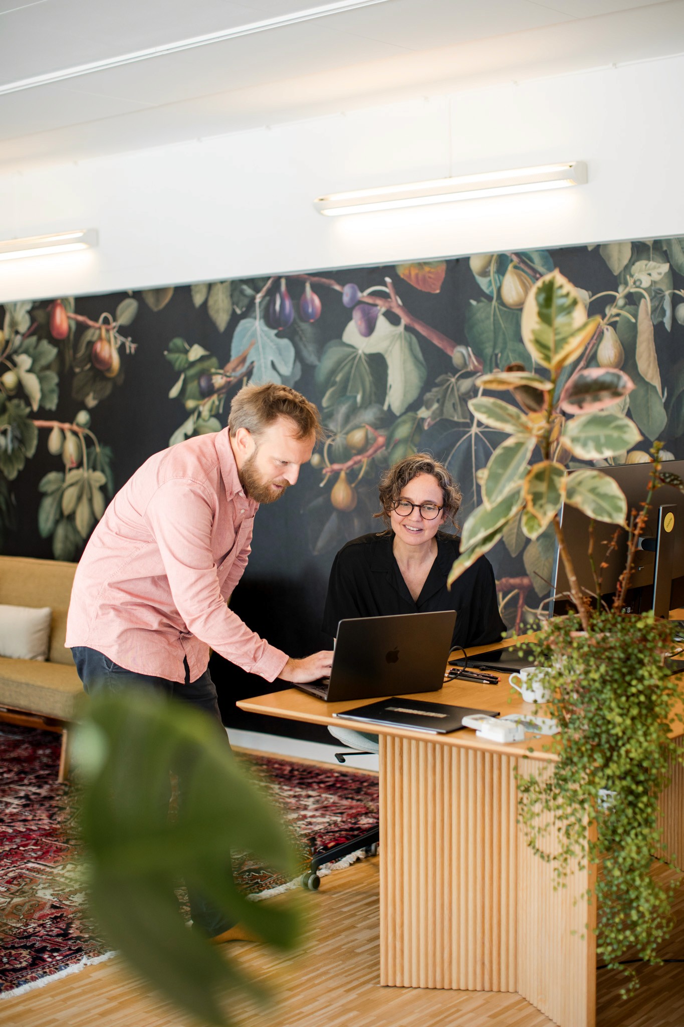 Smiling young man with short hair poses against a dark background, wearing a green button-up shirt.