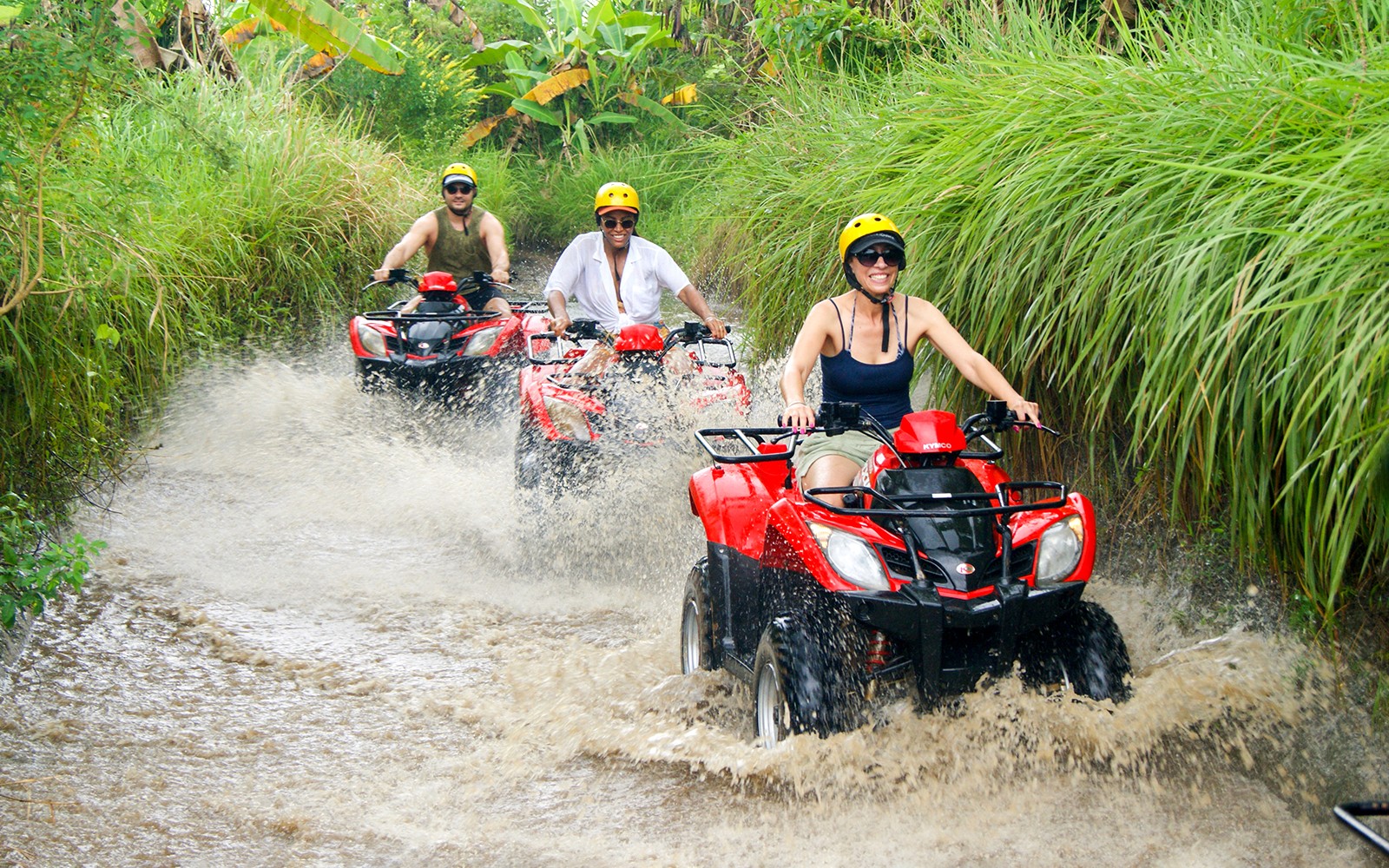 ATV riders navigating a muddy trail in Bali during a guided quad bike tour.