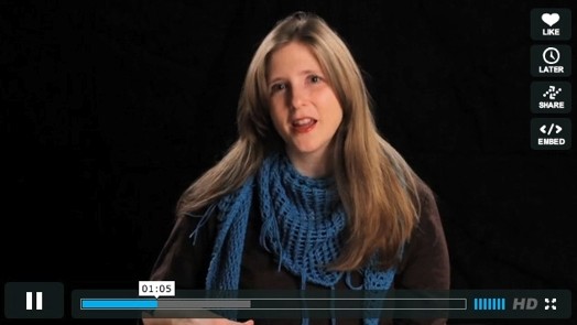 A still shot image of a woman wearing a green scarf and talking.