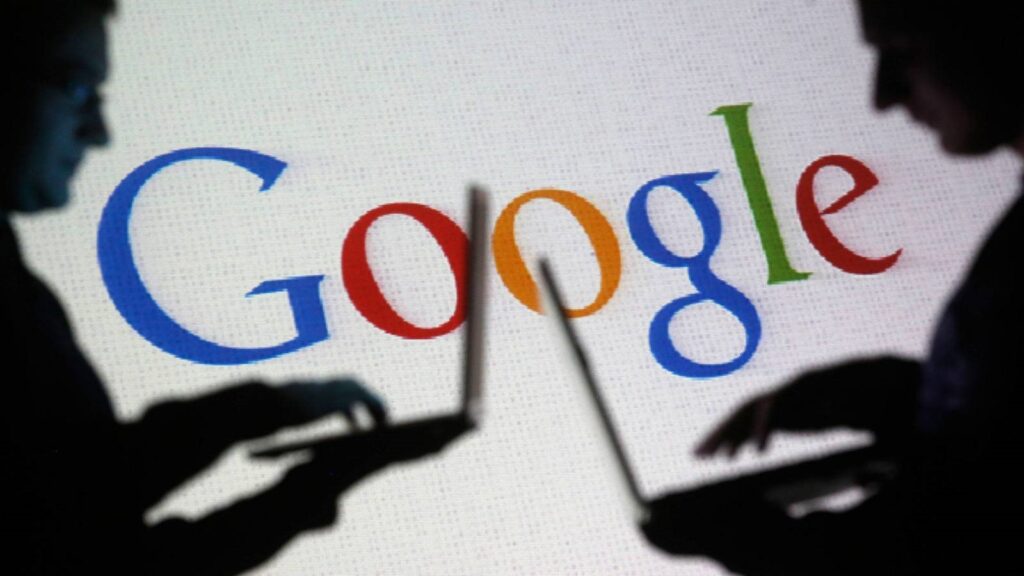 Silhouettes of two people using laptops with a large Google logo projected in the background, symbolizing online search and digital connectivity.