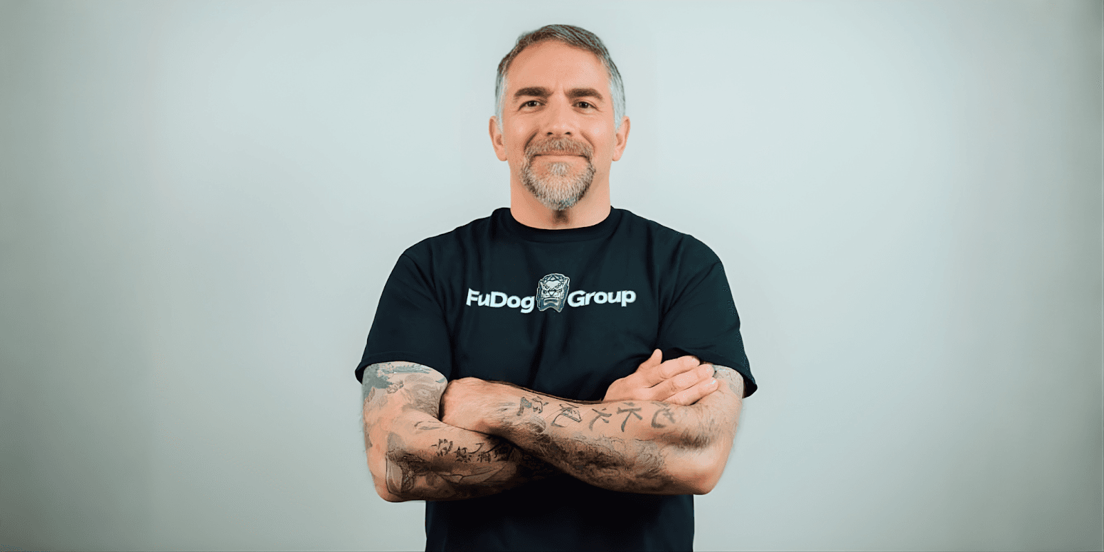 Mike Agugliaro, co-founder of FuDog Group, standing confidently in a black t-shirt, helping business owners scale and succeed.