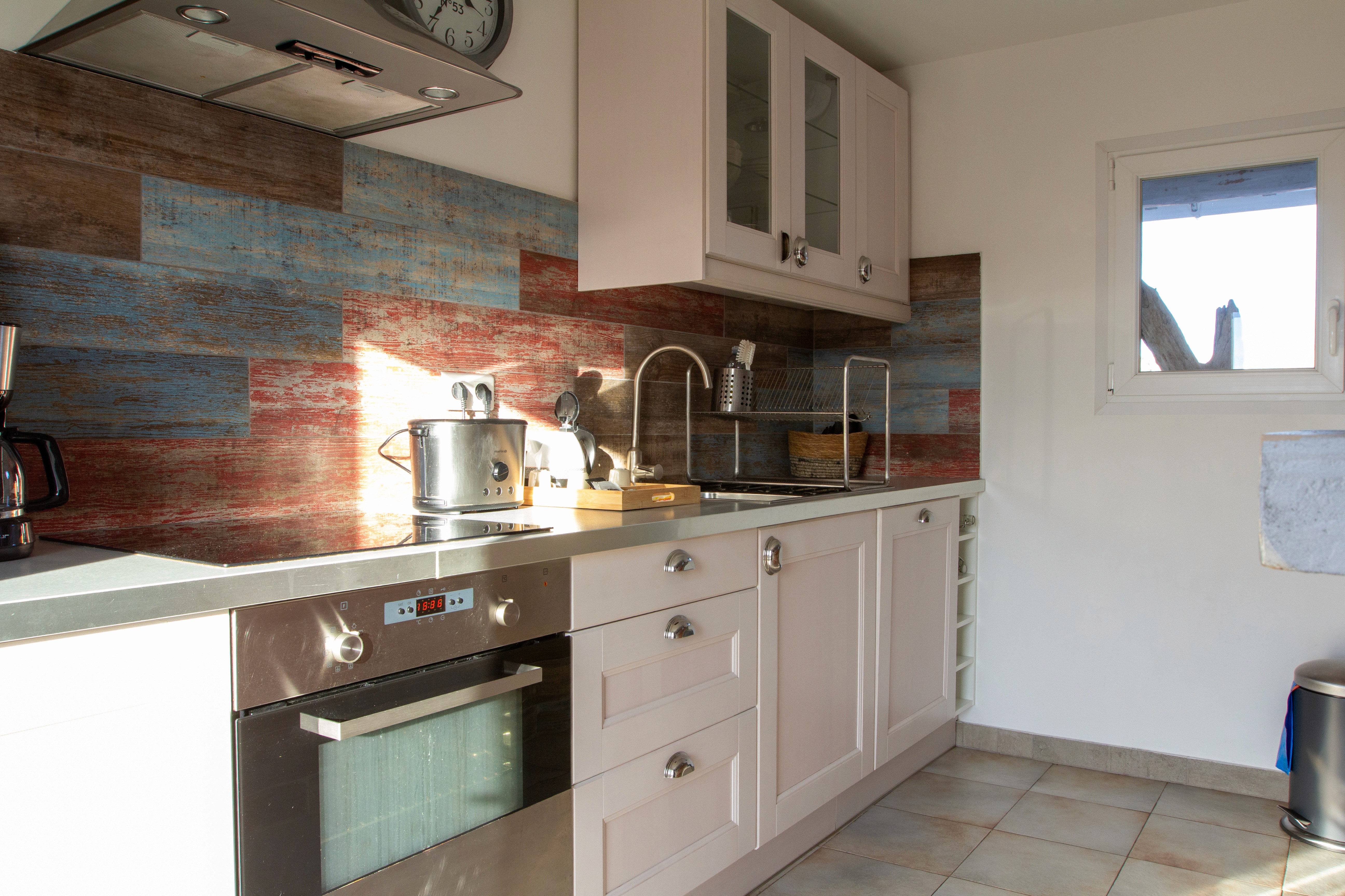 Décoration de salon bohème avec canapé gris, plantes vertes d'intérieur et vue sur un balcon aménagé par une porte-fenêtre lumineuse.