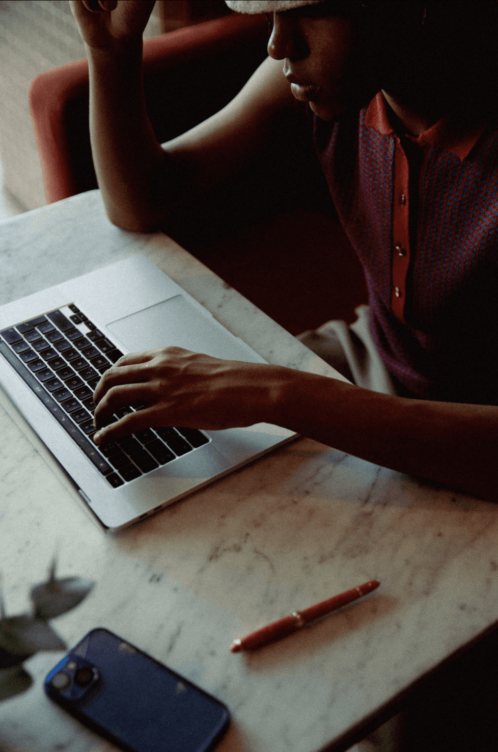 A woman in a striped shirt holds a credit card while using a laptop, bathed in warm sunlight in a cozy, modern setting.