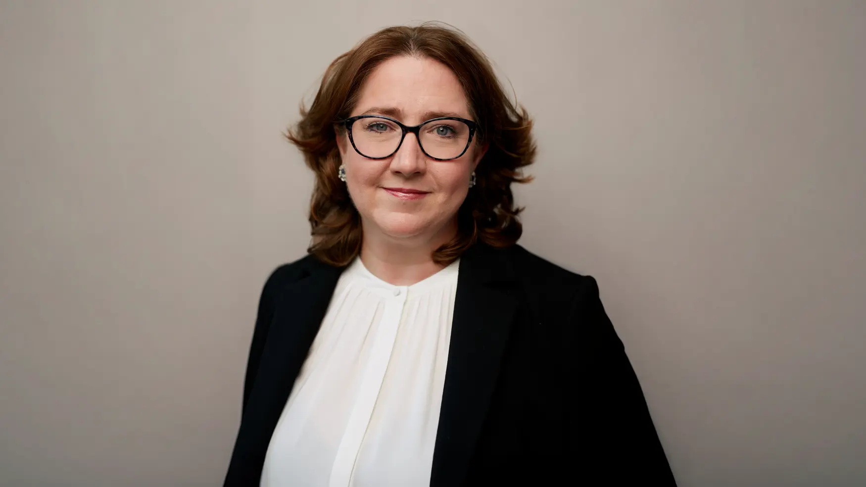 Kim Aiken on a grey background, in smart clothing