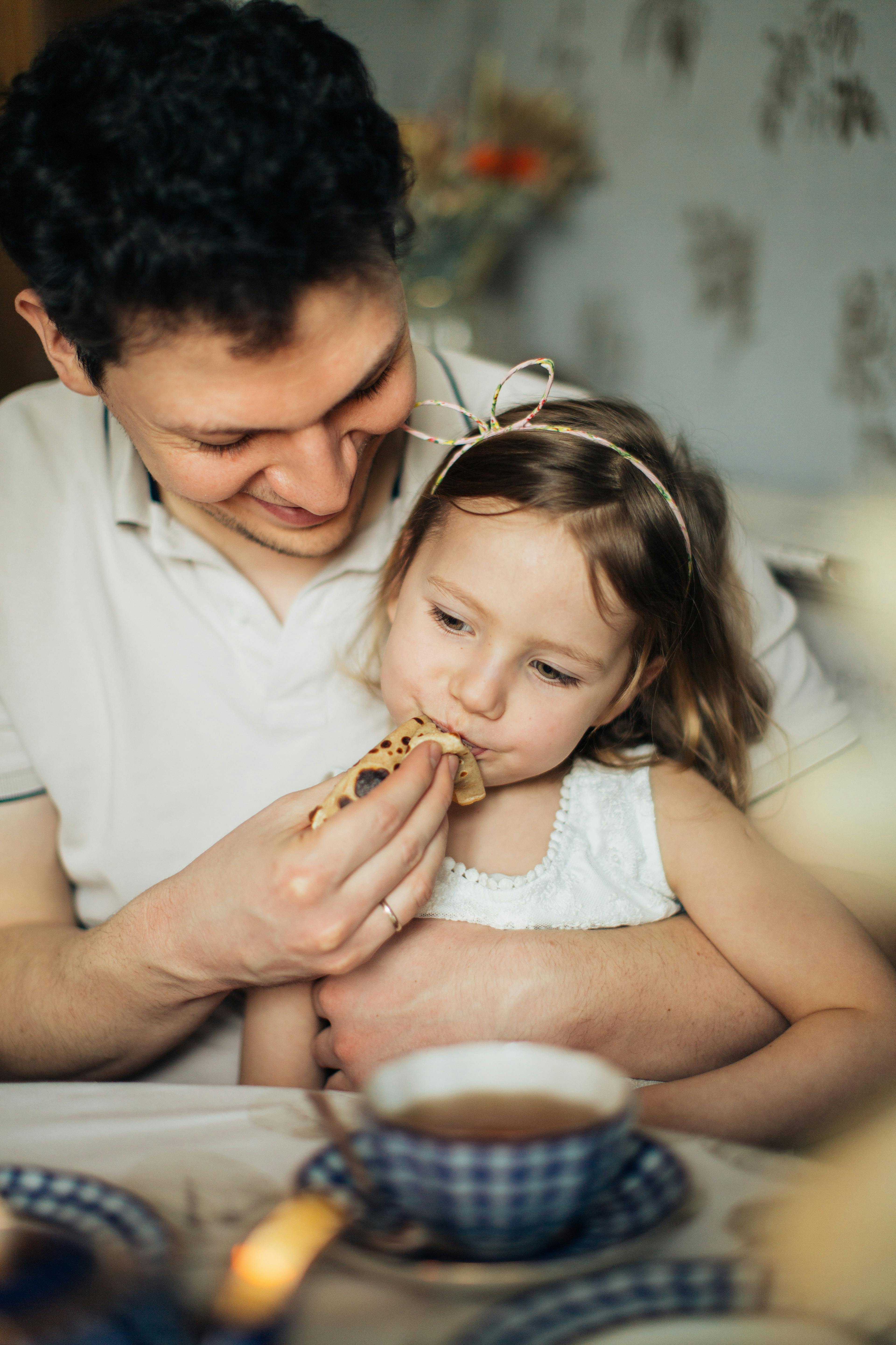 Father feeding his daughter with food