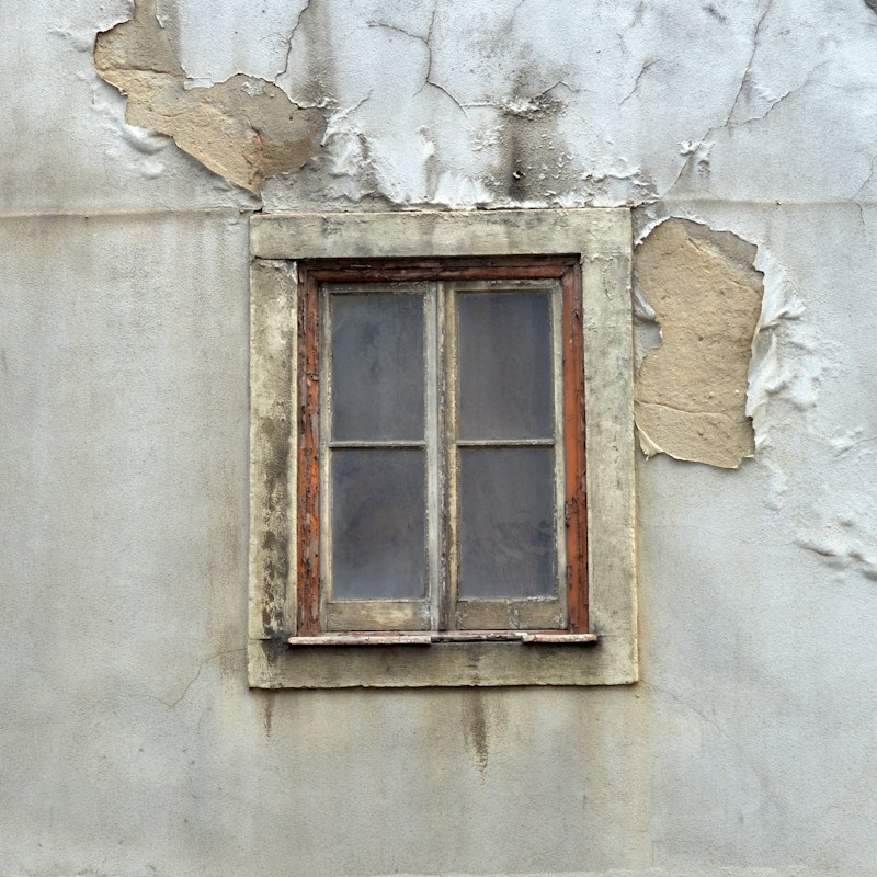 Close-up of a weathered, boarded-up window.