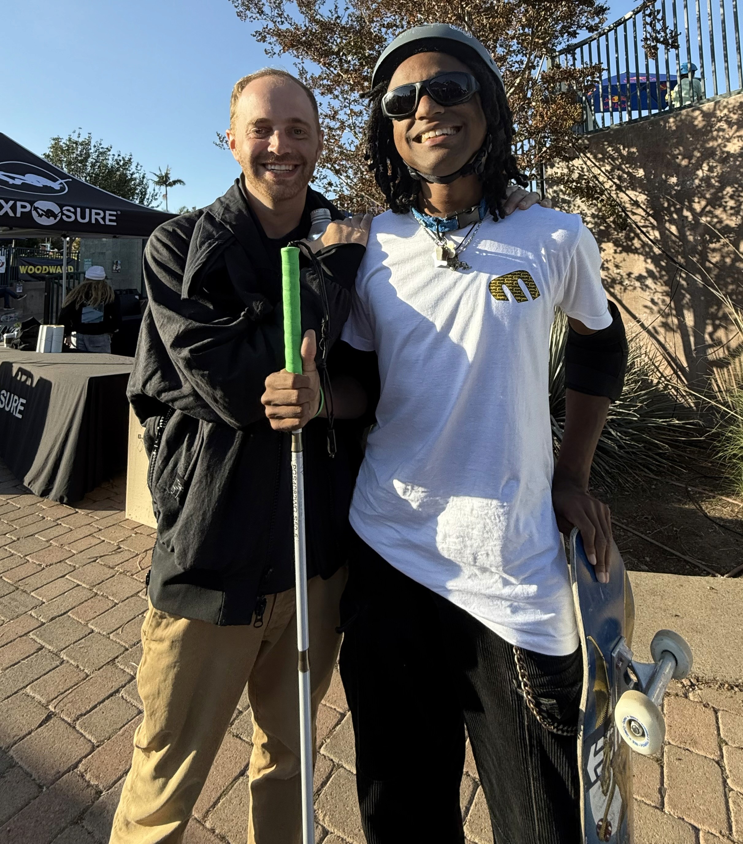 Photo of me next to Coco, with my arm around him. He is holding his skateboard and cane and we both have big grins on our faces