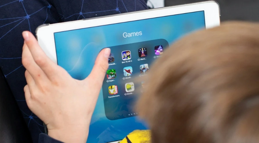 Bambino che utilizza un tablet con applicazioni di giochi, esempio di fuga negli schermi e regolazione emotiva attraverso la tecnologia