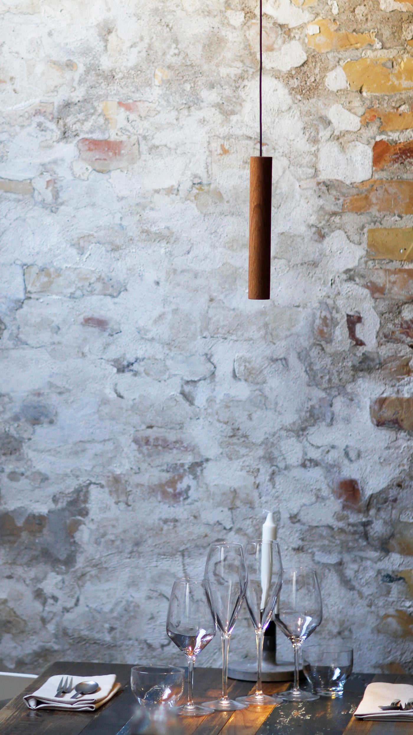 Chimes pendant lamp in solid oak suspended against textured brick wall designed by Asger Risborg Jakobsen