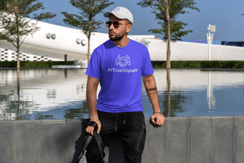 Man wearing AI Trust Signals logo T-shirt and cap, looking towards a laptop displaying the AI Trust Signals logo on its screen, set against a modern outdoor backdrop.