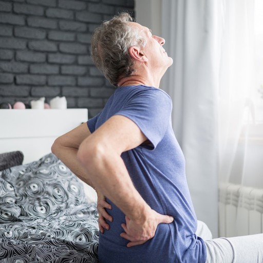 man holding his lower back in bed