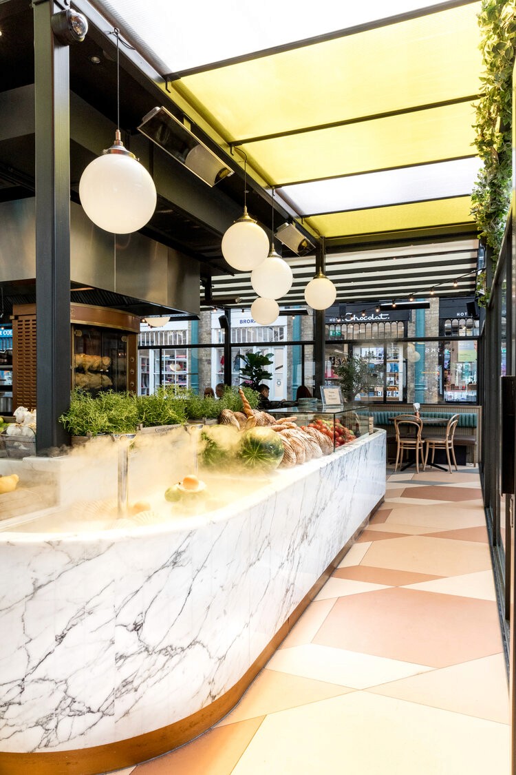 A bright café with a long marble counter, warm lighting, and contemporary decor.