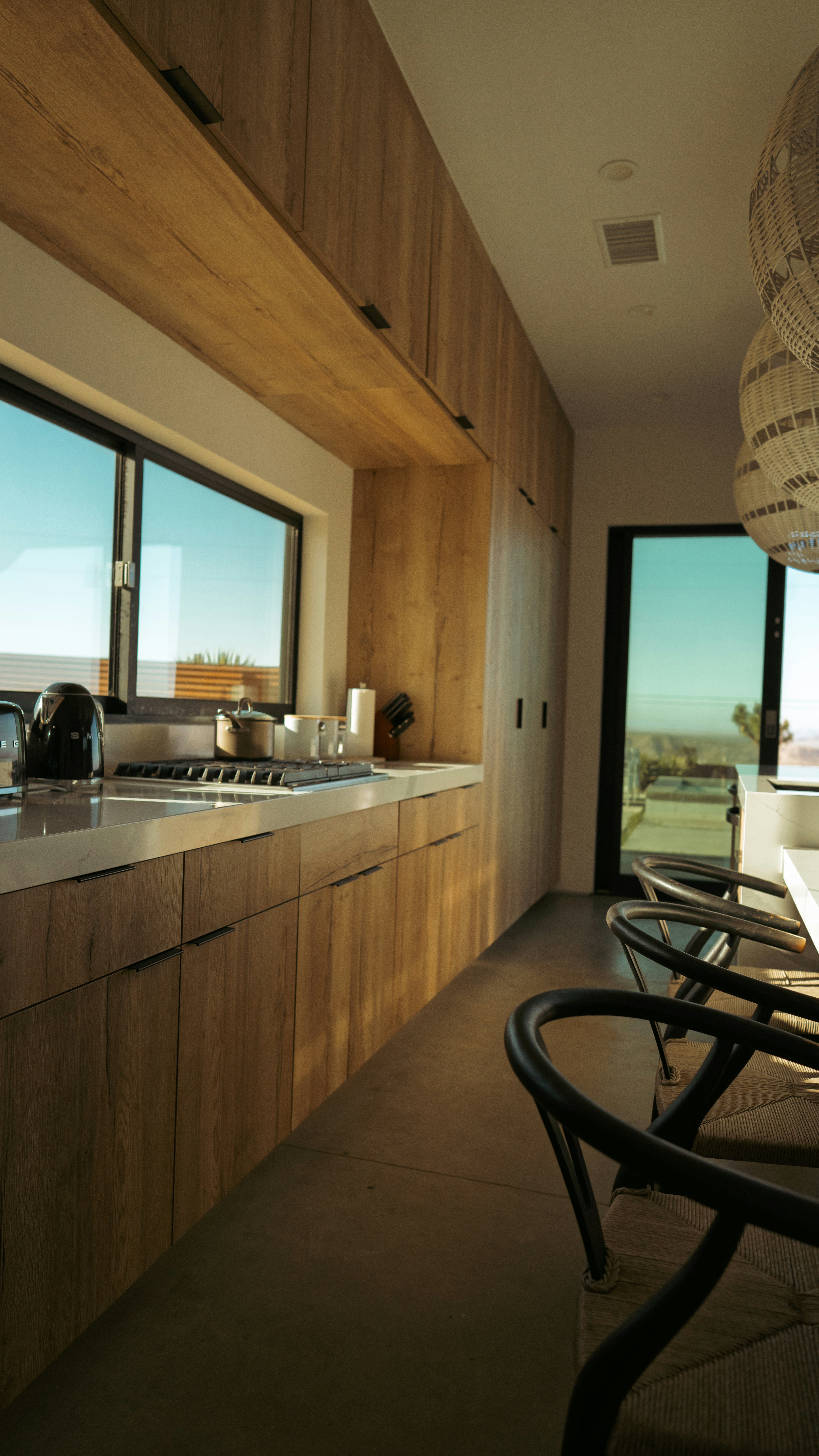 Modern kitchen with wooden cabinets and large windows.