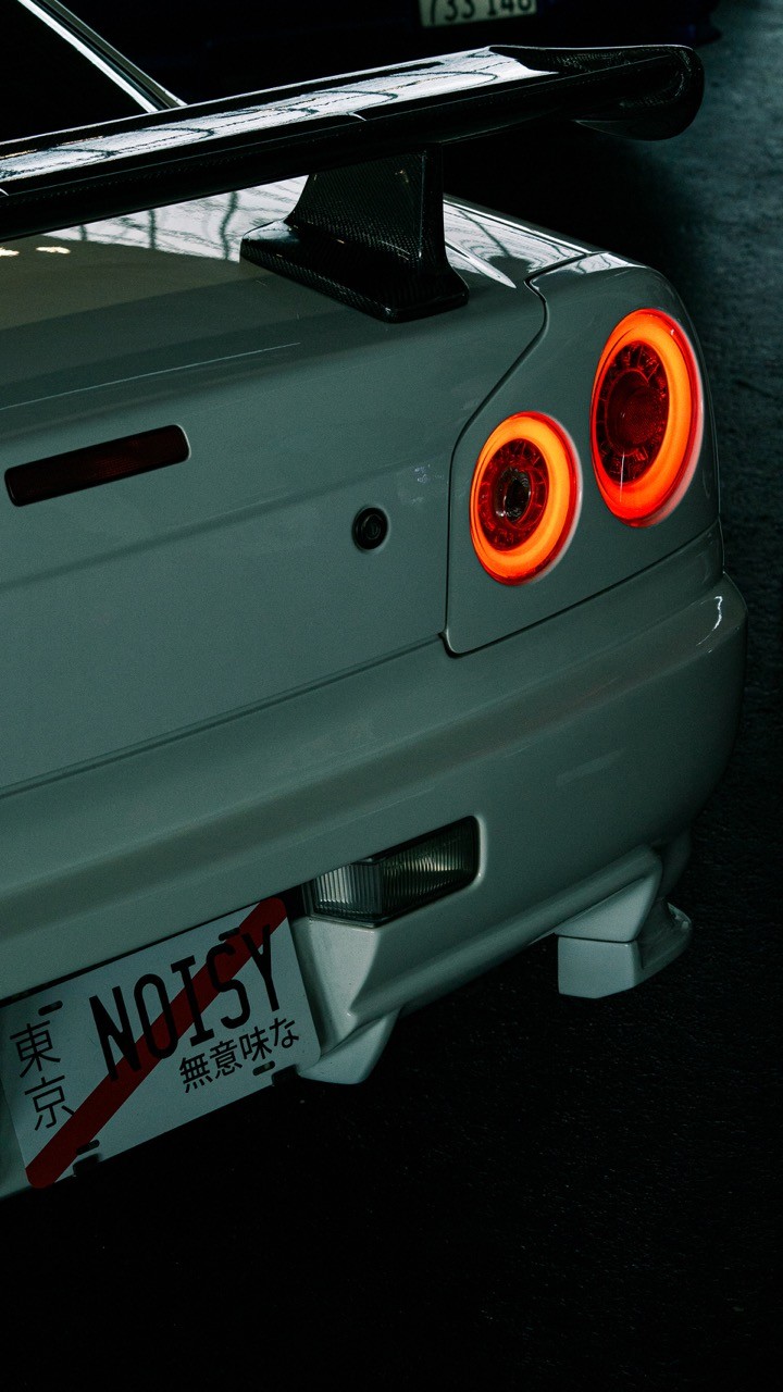 Close-up of a sleek sports car's rear, featuring distinctive round taillights and a sporty exhaust system.