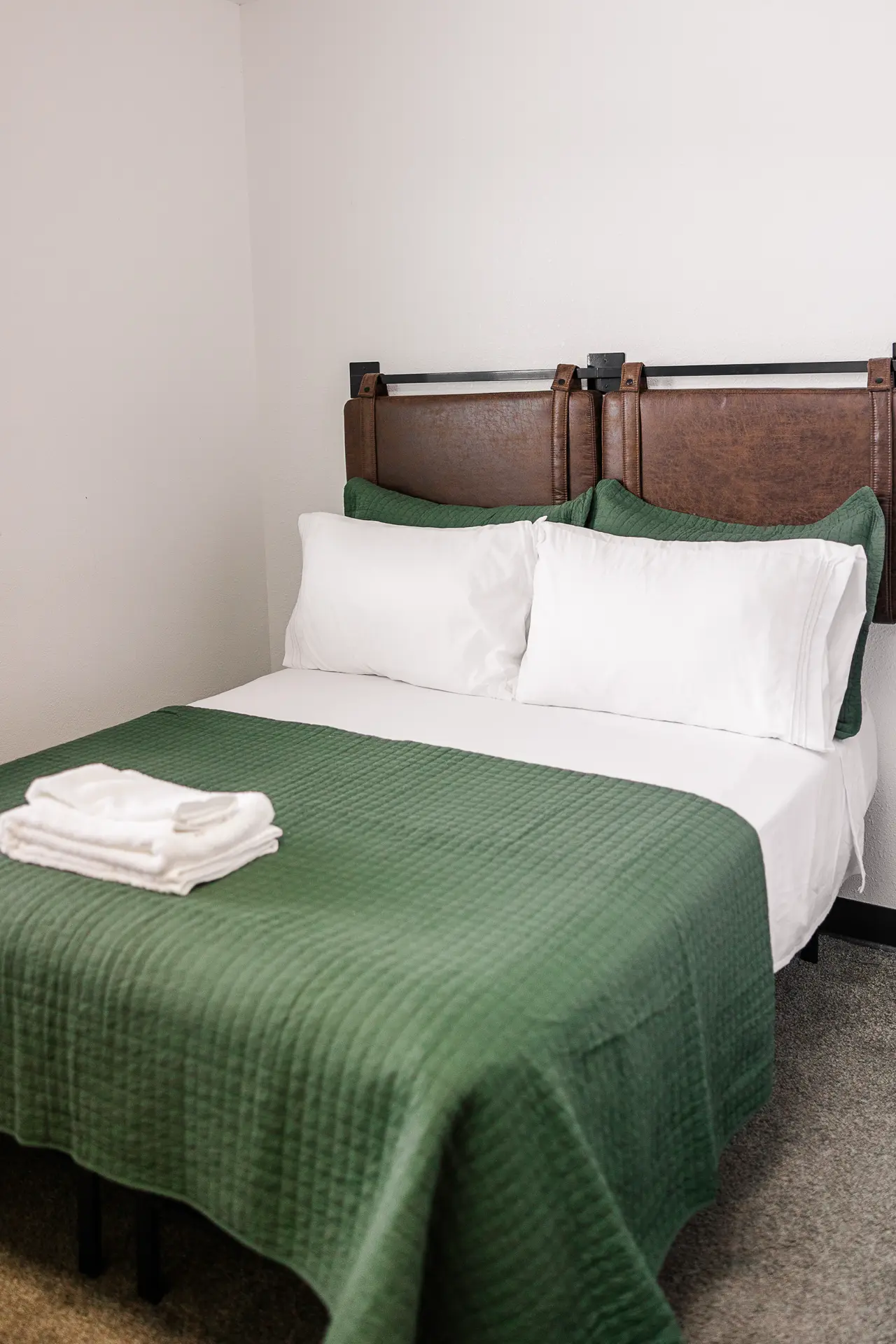Trophy Lodge guest room with green quilt, white pillows, and fresh towels.