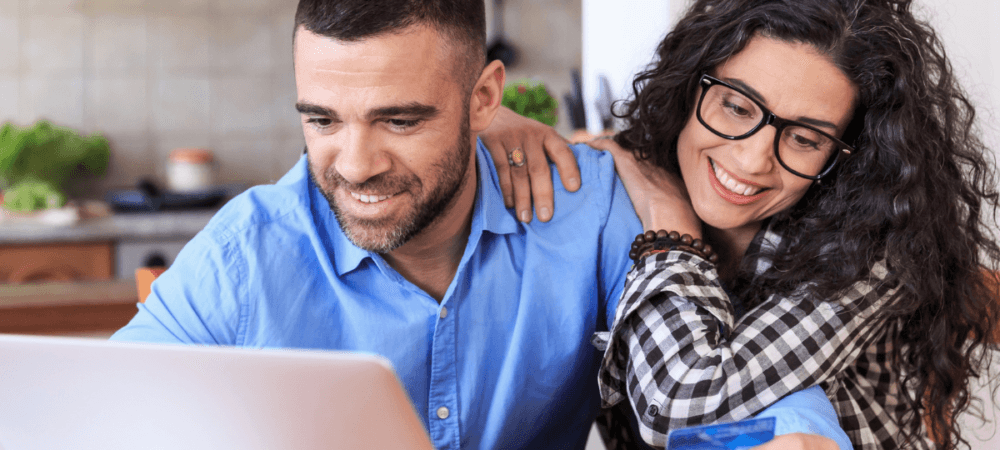 Beginner investor couple smiling and looking at computer