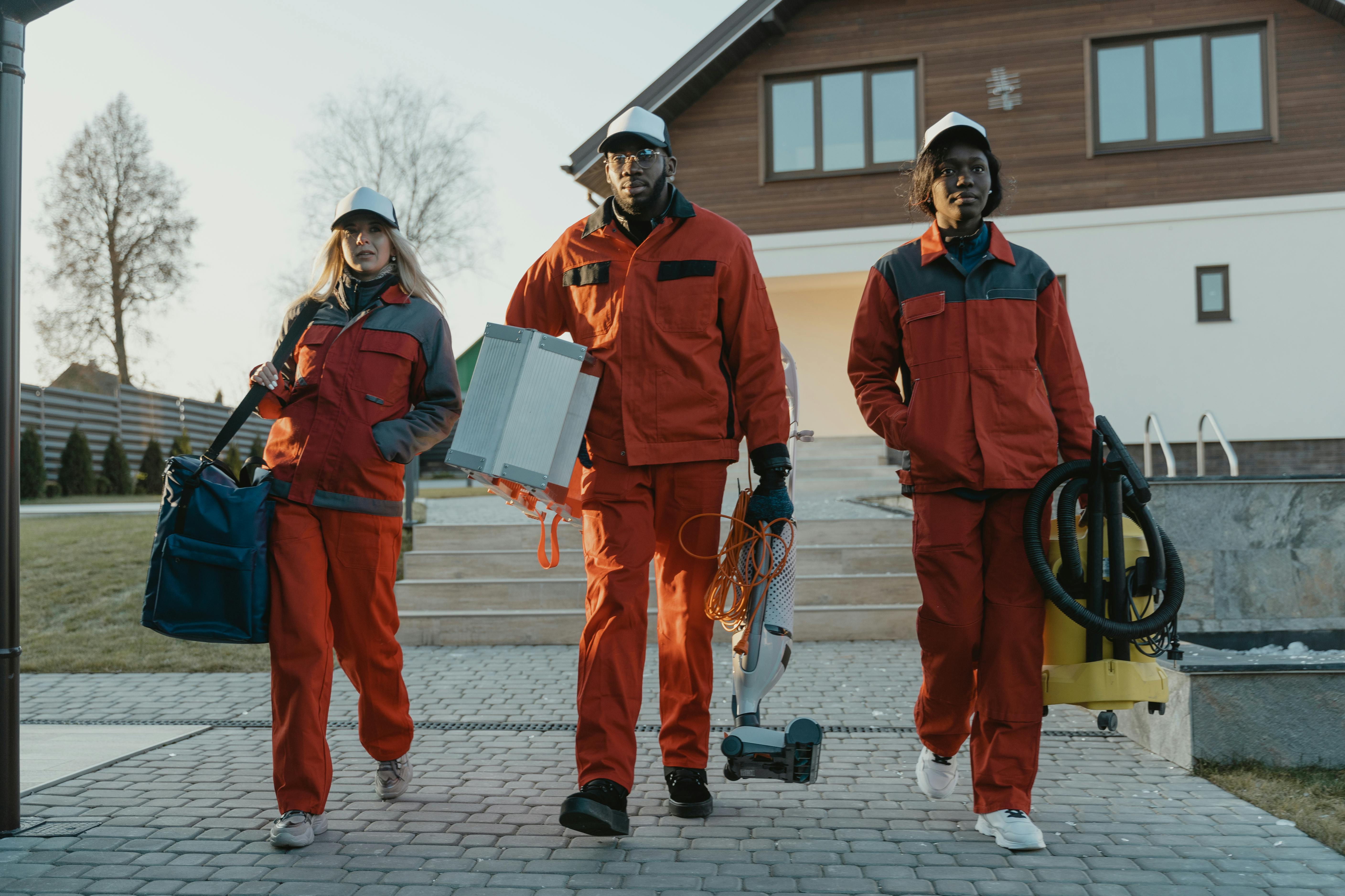 Three cleaning team members in matching red uniforms walking together, showing business growth and team expansion