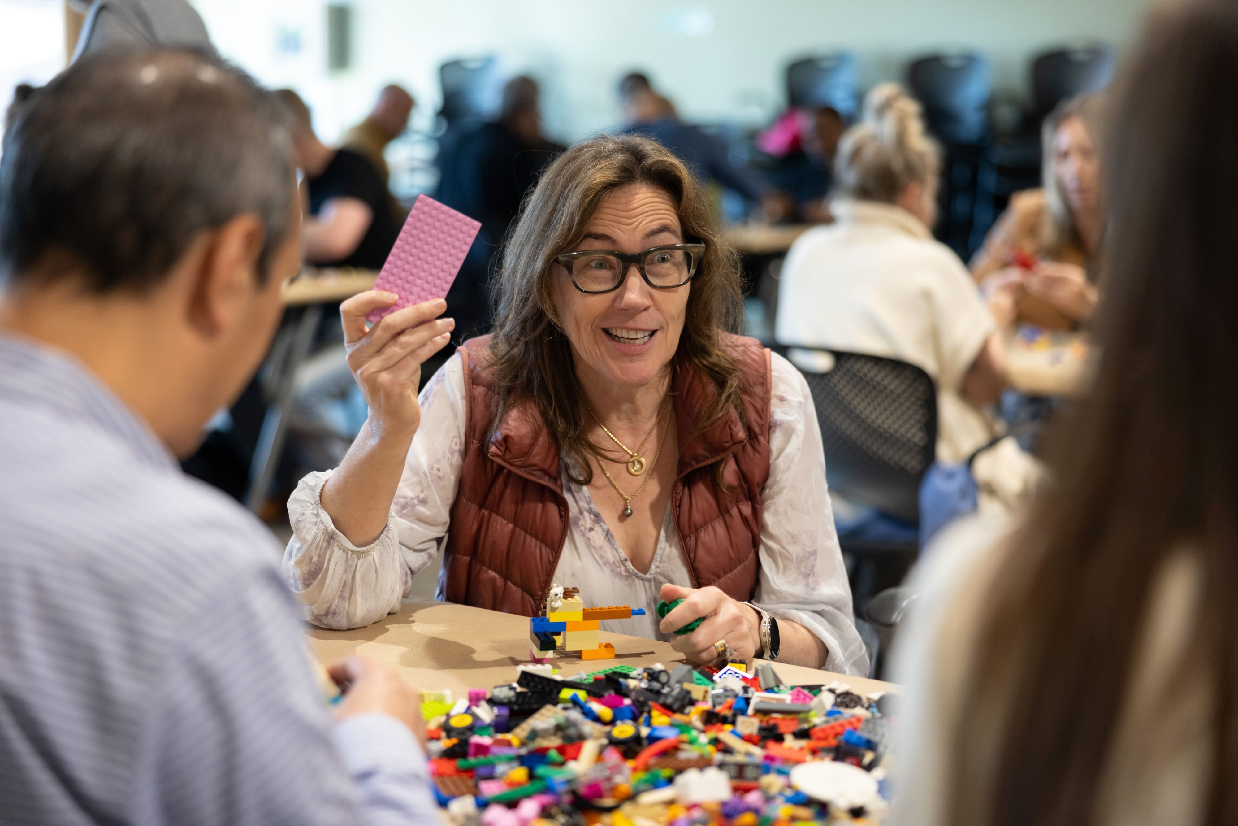 A woman holding up a card during a Lego exercise at the Artificiality Summit