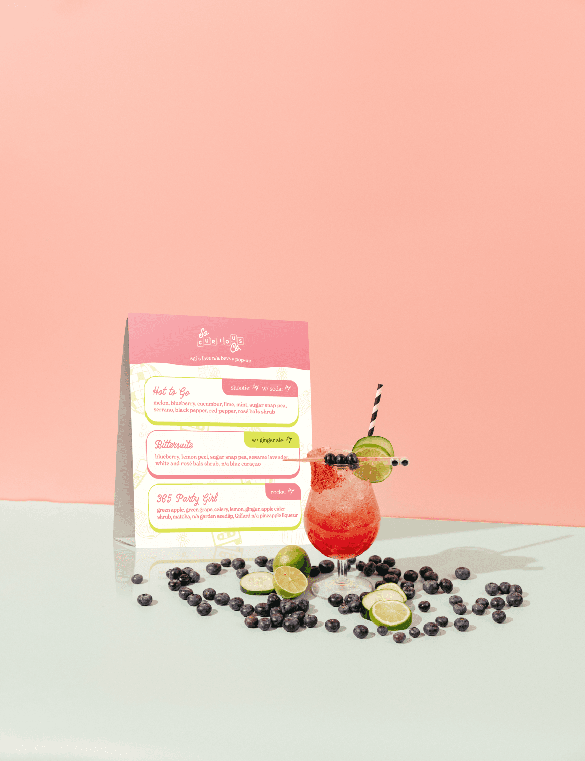 A mockup of a So Curious Co menu design in a scene with one of their signature non-alcoholic drinks