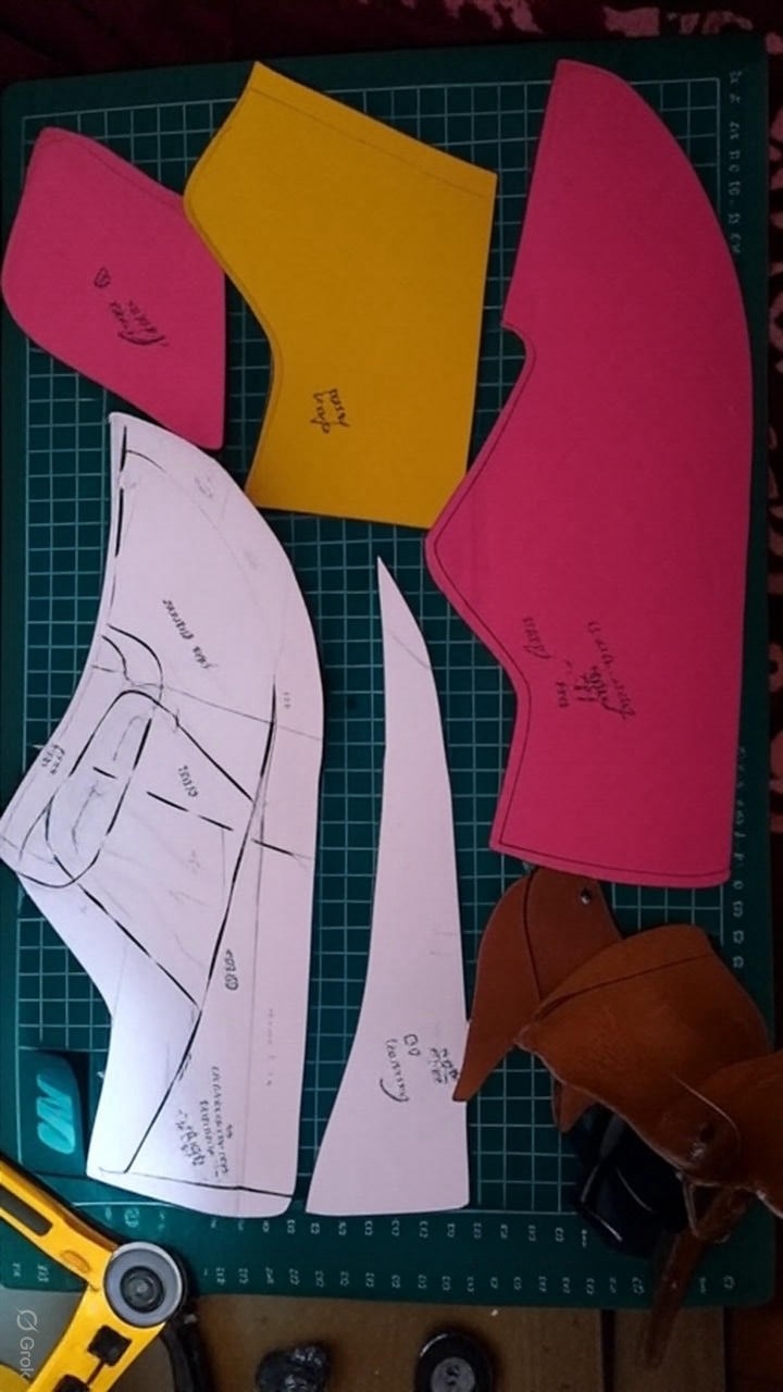 Una persona con una camiseta negra y pantalones de color claro está de pie en la cima rocosa de una montaña al atardecer, sosteniendo una cámara frente a su cara para tomar una foto. Un mar de nubes se extiende detrás de ellos, iluminado por la luz dorada del sol poniente.