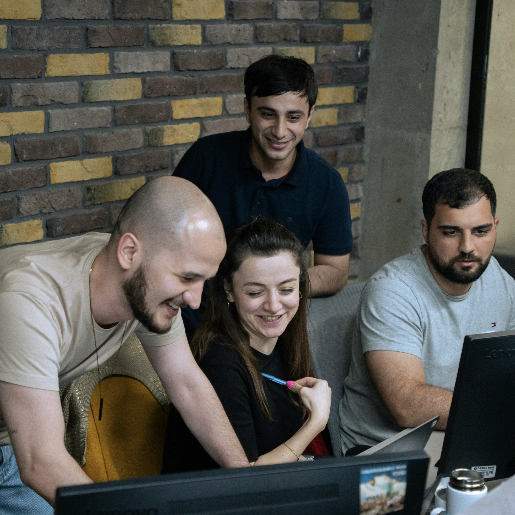 A group of people looking at a laptop and smiling