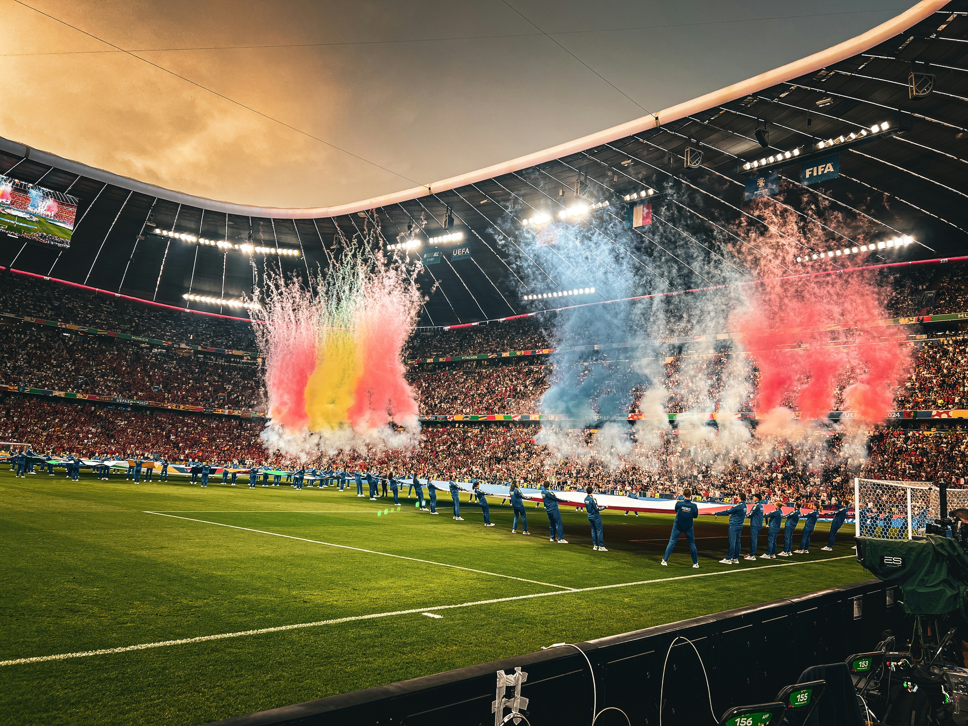 Tri-colored smoke, depicting the national flags of Spain and France, erupting in front of a filled football stadium.