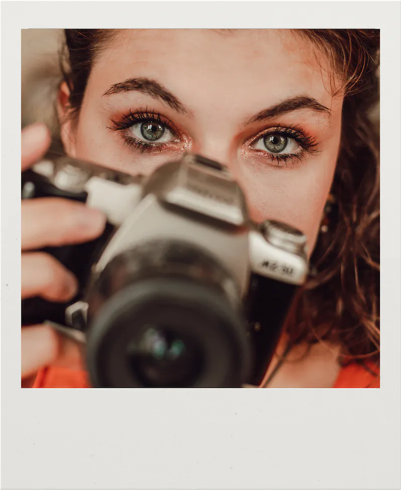 Photo portrait de Anne lise tenant un appareil photo en format carré polaroïde