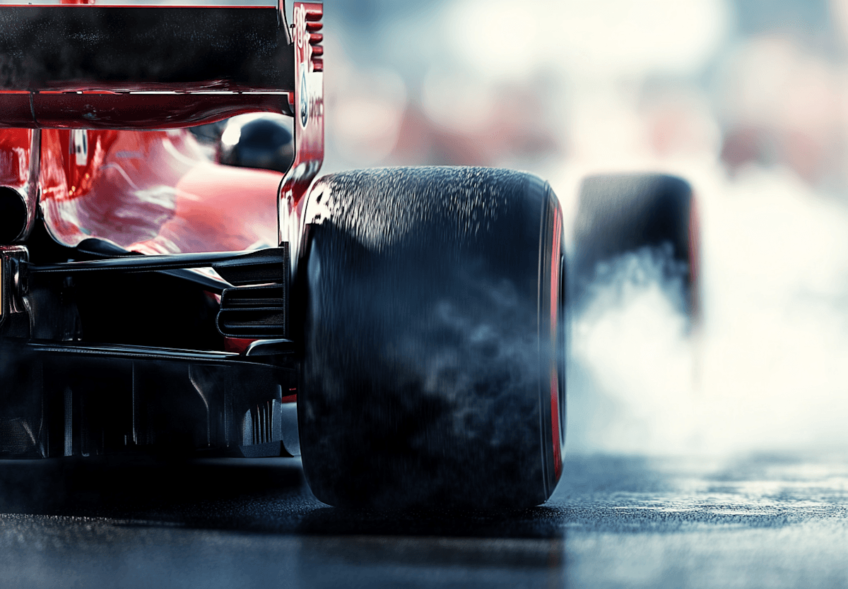 Close-up of a racing car's rear tire, smoke billowing as it accelerates on the track.