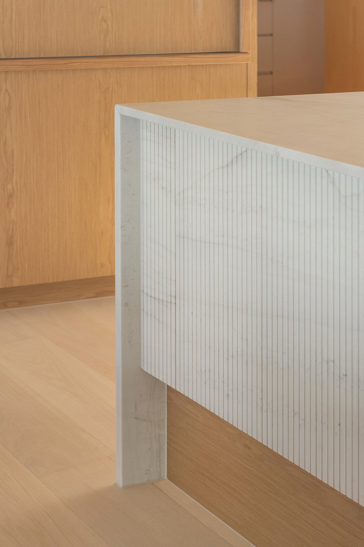 Detail of custom marble kitchen island with fluted stone face and timber base in High Tide apartment, Surfers Paradise.