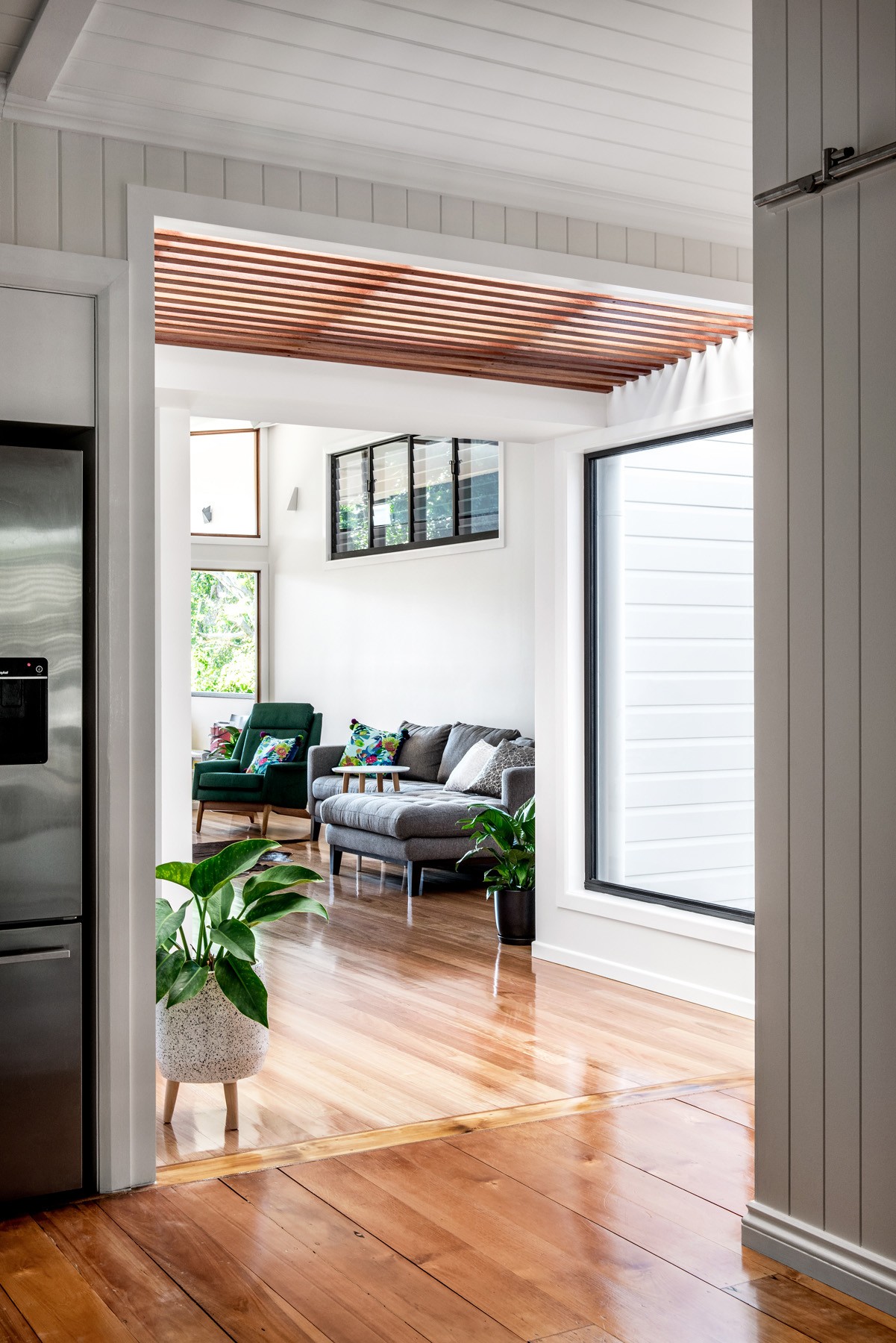Transition between old and new at Oxford Cottage, where lined walls and a timber ceiling element frame the connection to the extended living area.