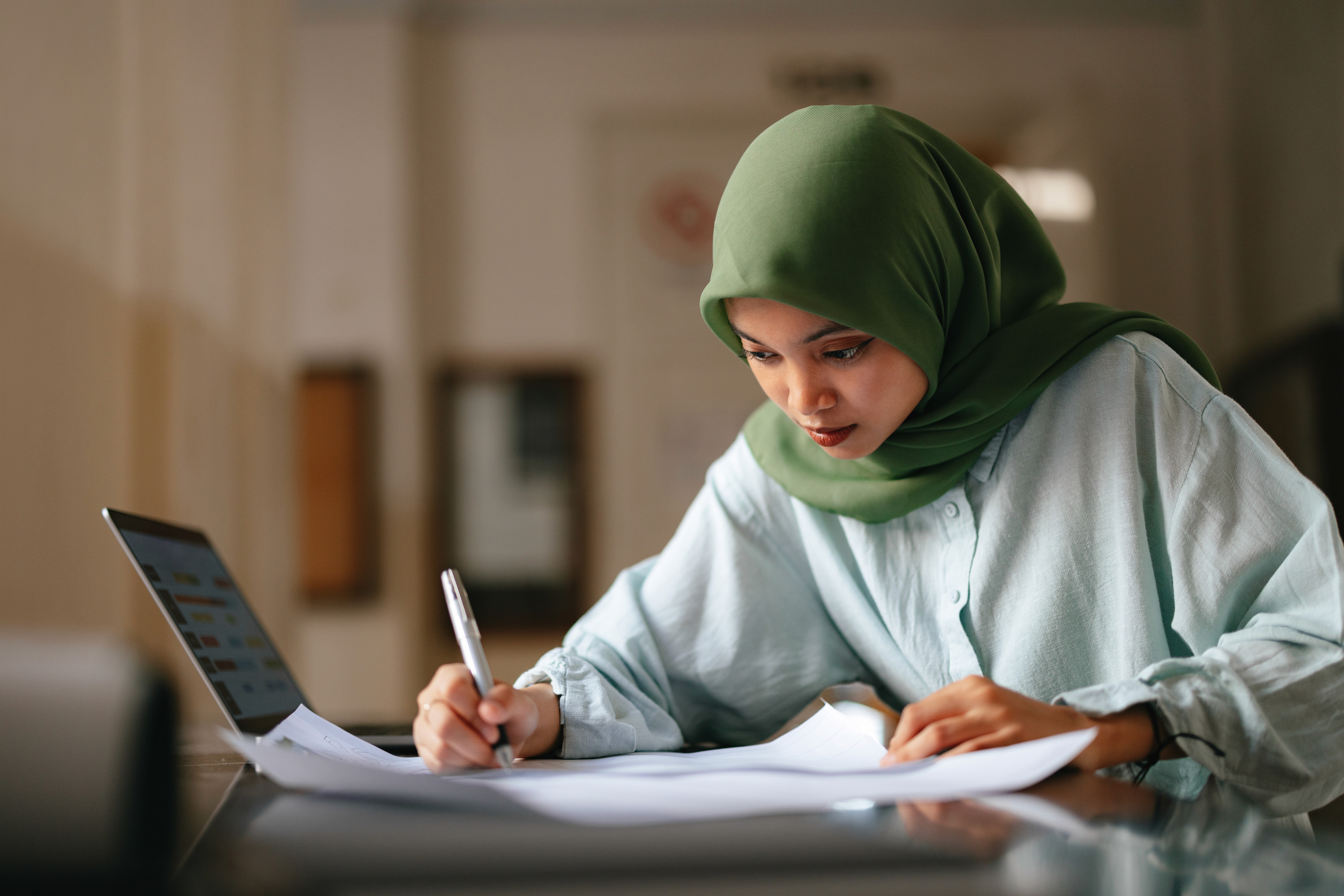 Smiling businesswoman shaking hands with someone across a table in an office setting.