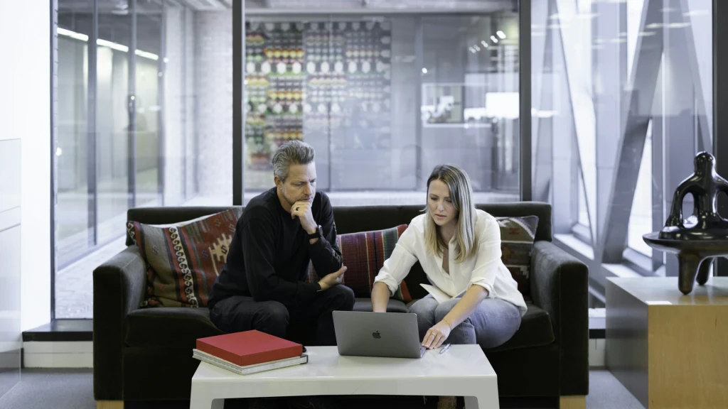 Berater im Gespräch mit Laptop vor Skyline – Symbolbild für M&A im Gesundheitswesen als Schlüssel zur Skalierung